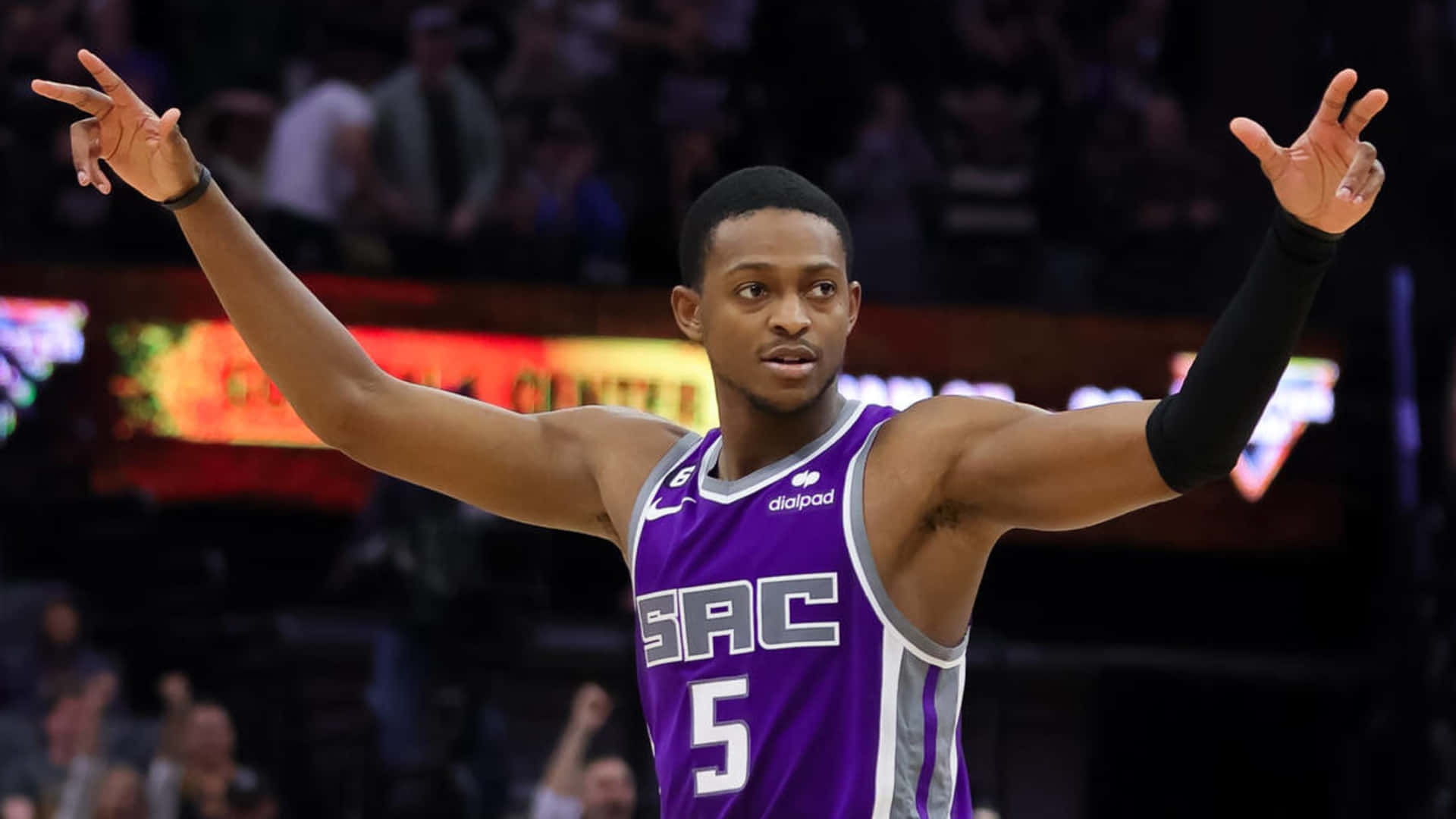 身穿紫色球衣的籃球運動員在比賽中高舉雙臂慶祝。 — NBA 壁紙