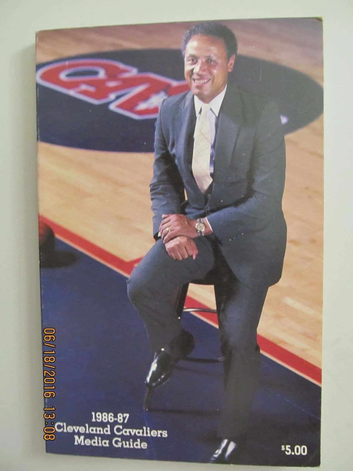 西裝男子在籃球場上微笑，帶有 Cavaliers 標誌。 — NBA 壁紙