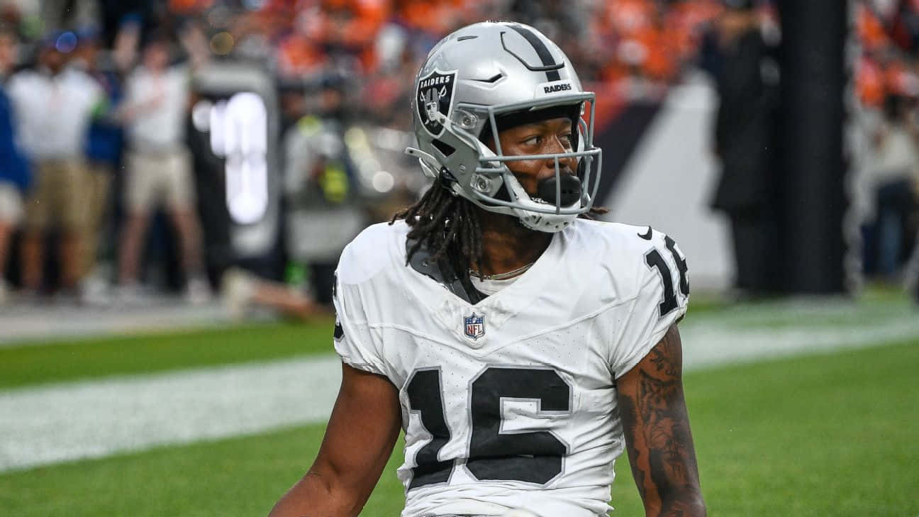  壁紙 — 一名專注的NFL美式足球員，身穿白色Raiders球衣（16號），在比賽期間於綠色球場上行走。