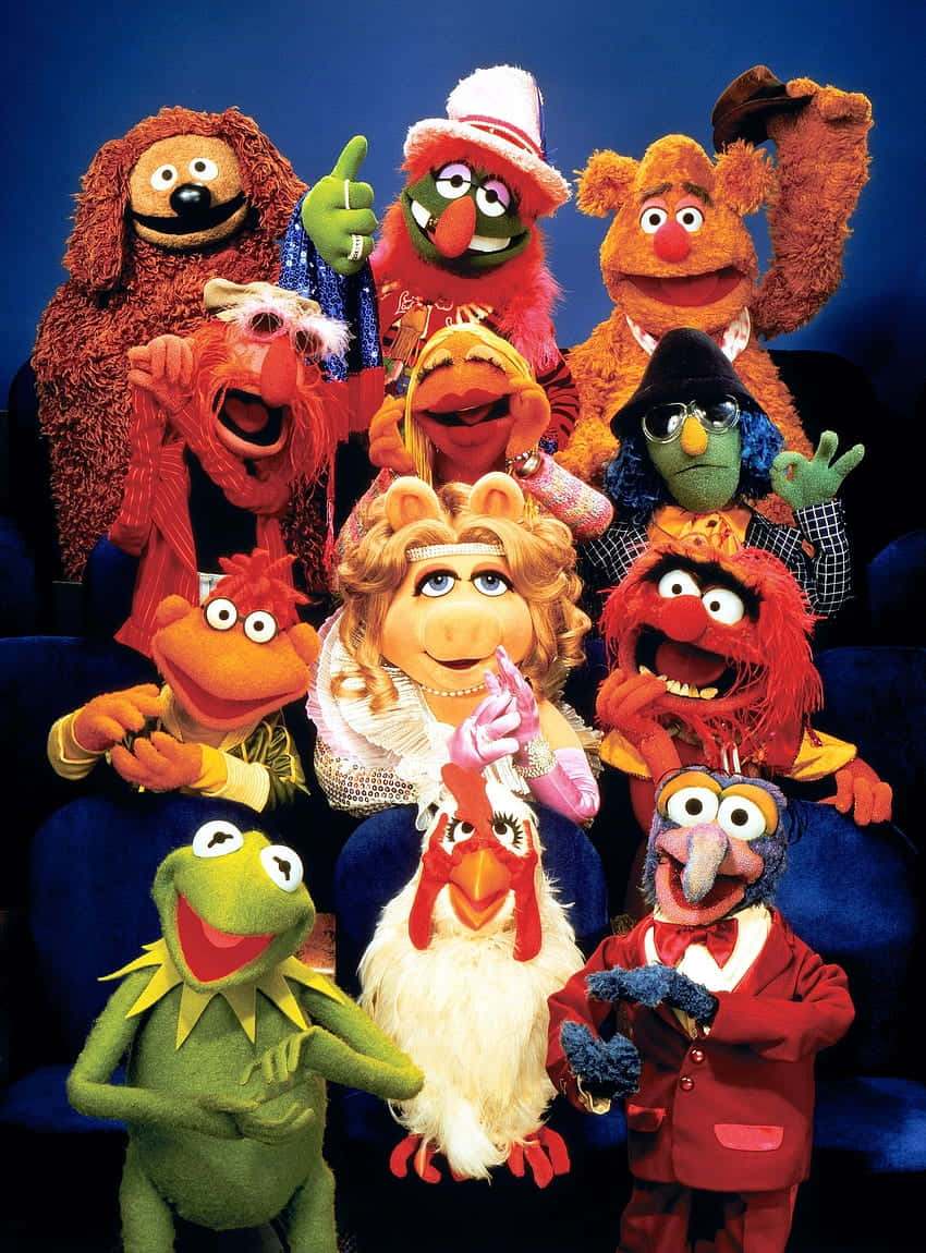  壁紙 — 一群色彩繽紛的Muppets在深藍色背景的劇院座位上愉快地擺姿勢。