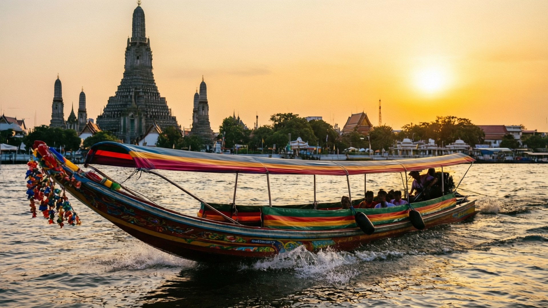 River Boat at Sunset 壁紙 — 一艘色彩繽紛的長尾船帶著彩虹頂篷在夕陽的水面上滑行，背後是鄭王廟在金色光芒中的剪影。