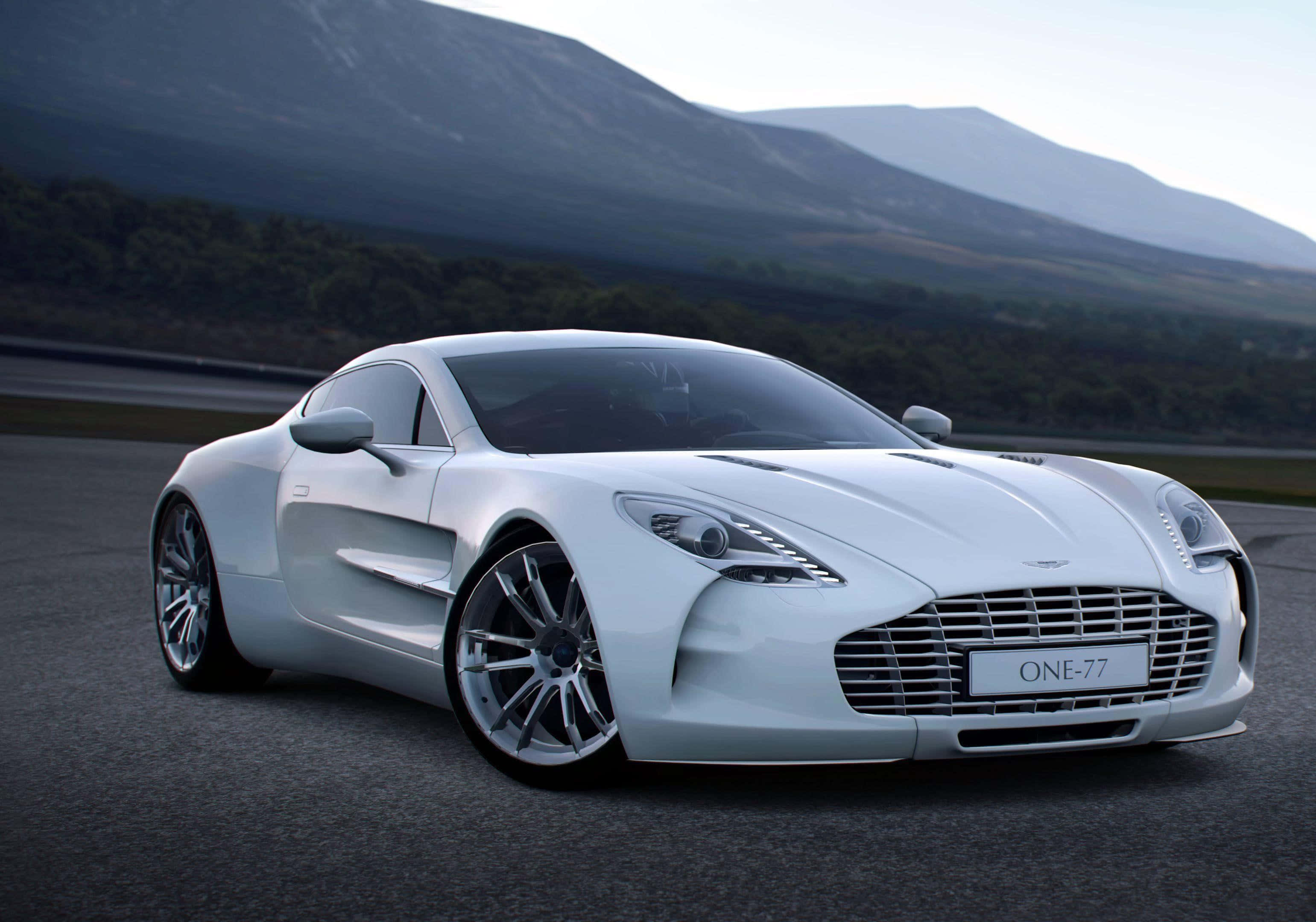 Aston Martin One-77 桌布 壁紙 — 一台流線型的白色Aston Martin One-77跑車在賽道上奔馳，背景是霧氣繚繞的山巒。