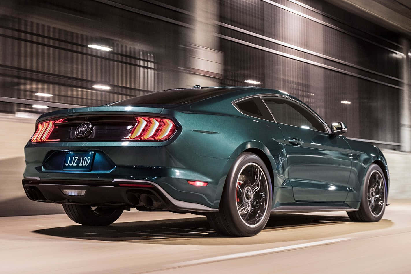 Ford Mustang Bullitt 桌布 壁紙 — 一台流線型青綠色福特野馬在燈光昏暗的隧道中疾馳，尾燈閃爍，帶有動態模糊效果。