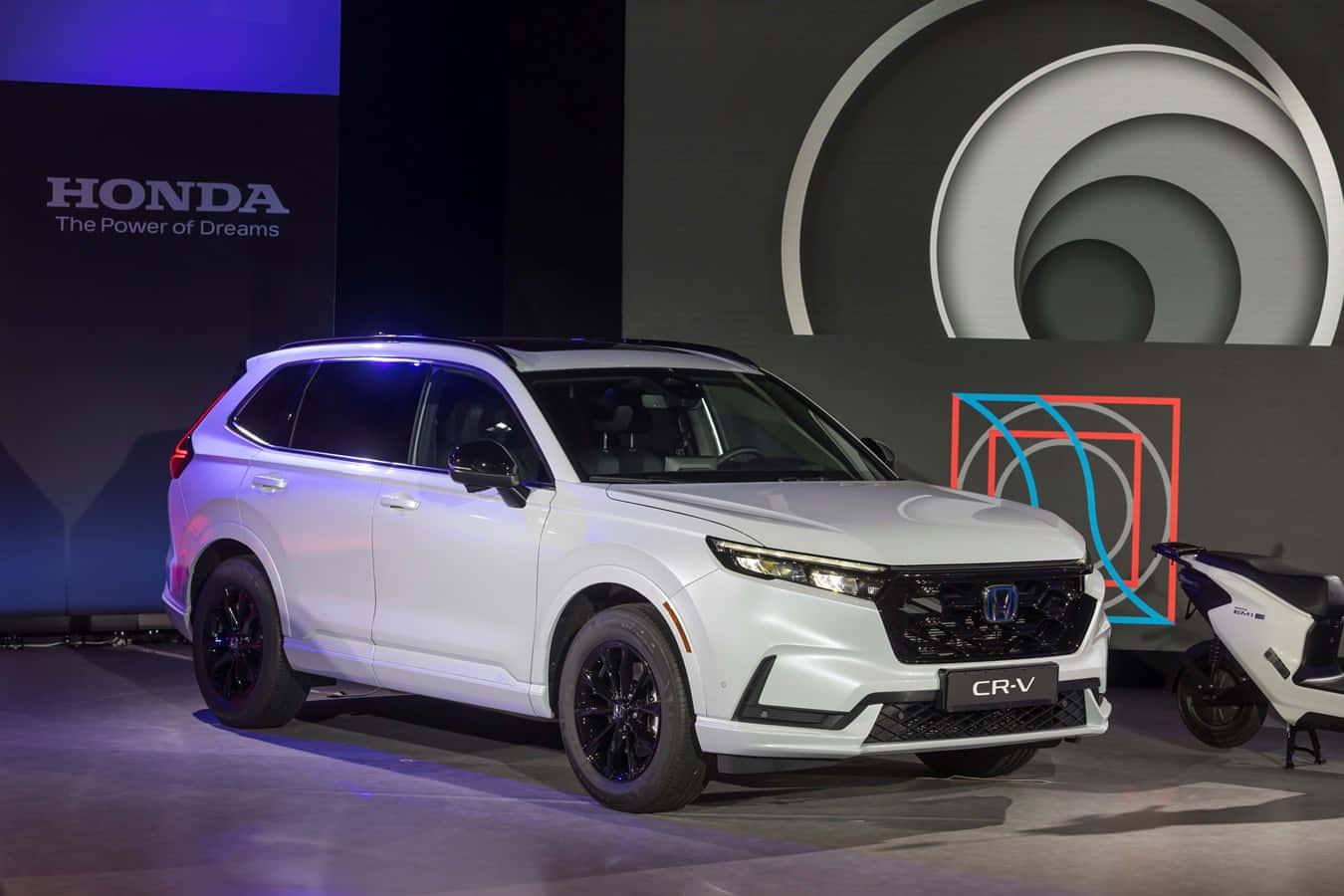 Honda Cr-v 桌布 壁紙 — 一台時尚的白色本田CR-V SUV在戲劇性的藍色燈光下，以幾何背景在舞台上展示。