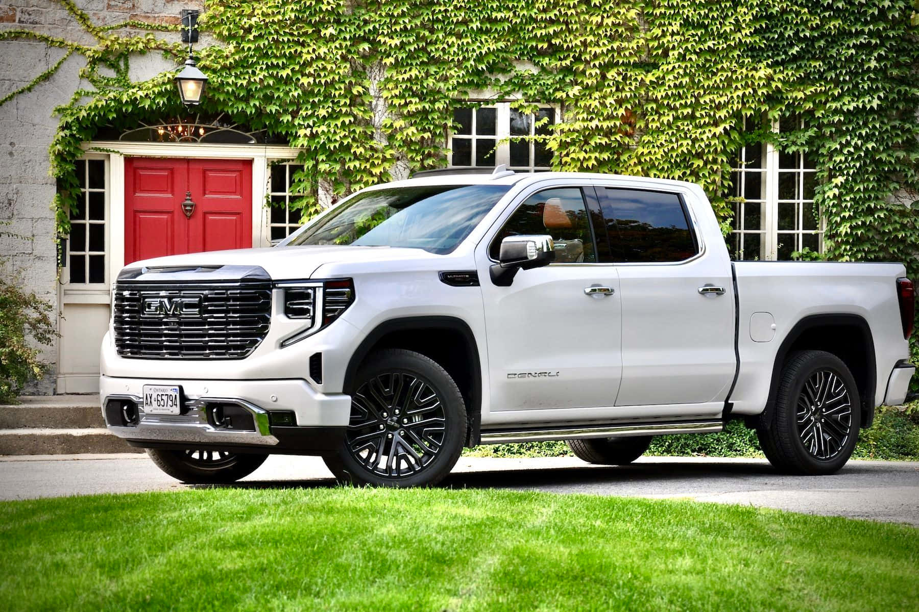 Gmc Sierra 桌布 壁紙 — 一台時尚的白色GMC Sierra Denali pickup truck停放在一間有紅色門、被藤蔓覆蓋的石屋前的車道上。