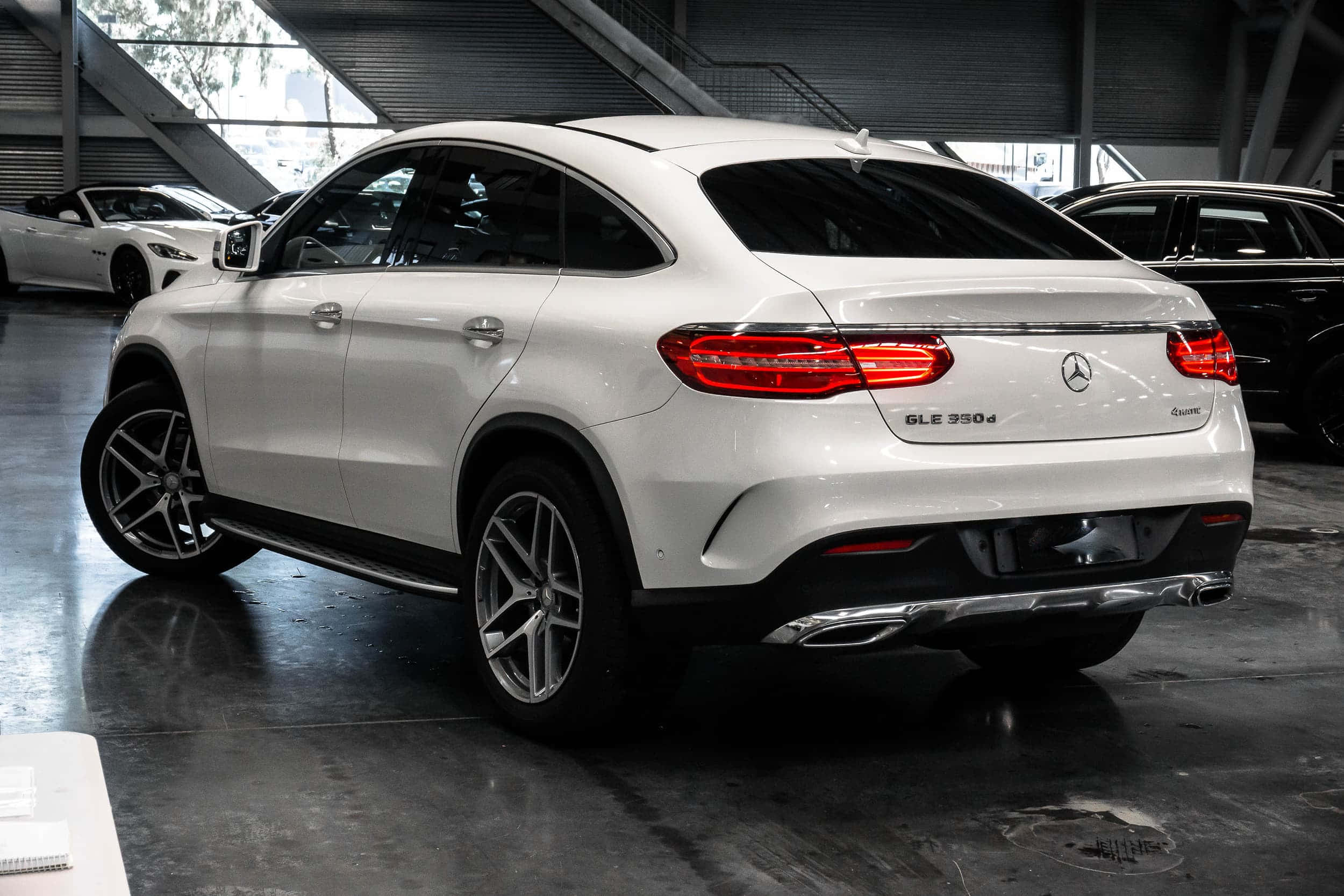 Mercedes Benz Gle-class 桌布 壁紙 — 一台時尚的白色 Mercedes-Benz GLE 350d Coupe 在現代汽車展示間的明亮燈光下閃閃發光，地板是拋光混凝土。
