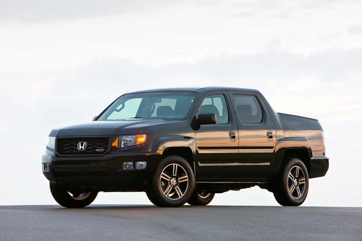 Honda Ridgeline 桌布 壁紙 — 一台時尚的黑色本田Ridgeline皮卡車停在鋪砌的路面上，柔和的多雲天空下，黃金時段的光線突顯其輪廓。