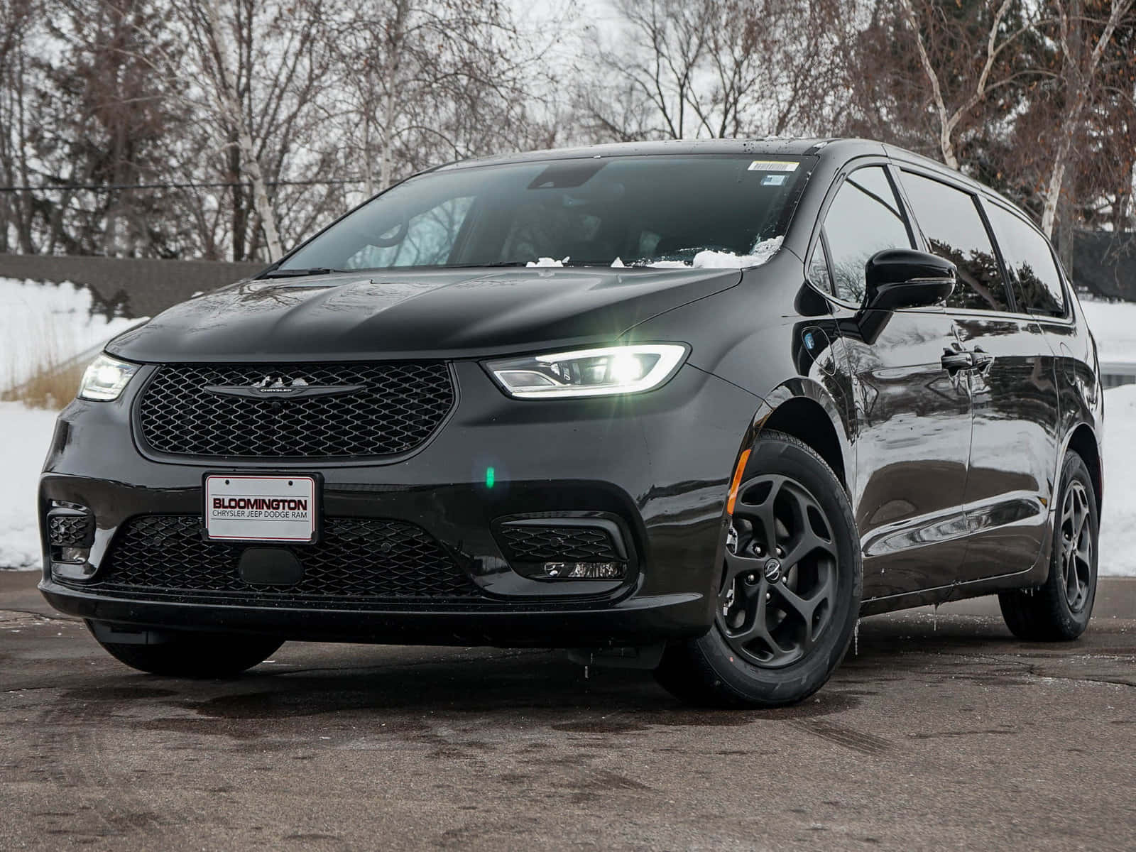 Chrysler Pacifica 桌布 壁紙 — 一台時尚的黑色克萊斯勒小型貨車在冬日陽光下閃閃發光，車頂上積雪，後面是光禿禿的樹木。