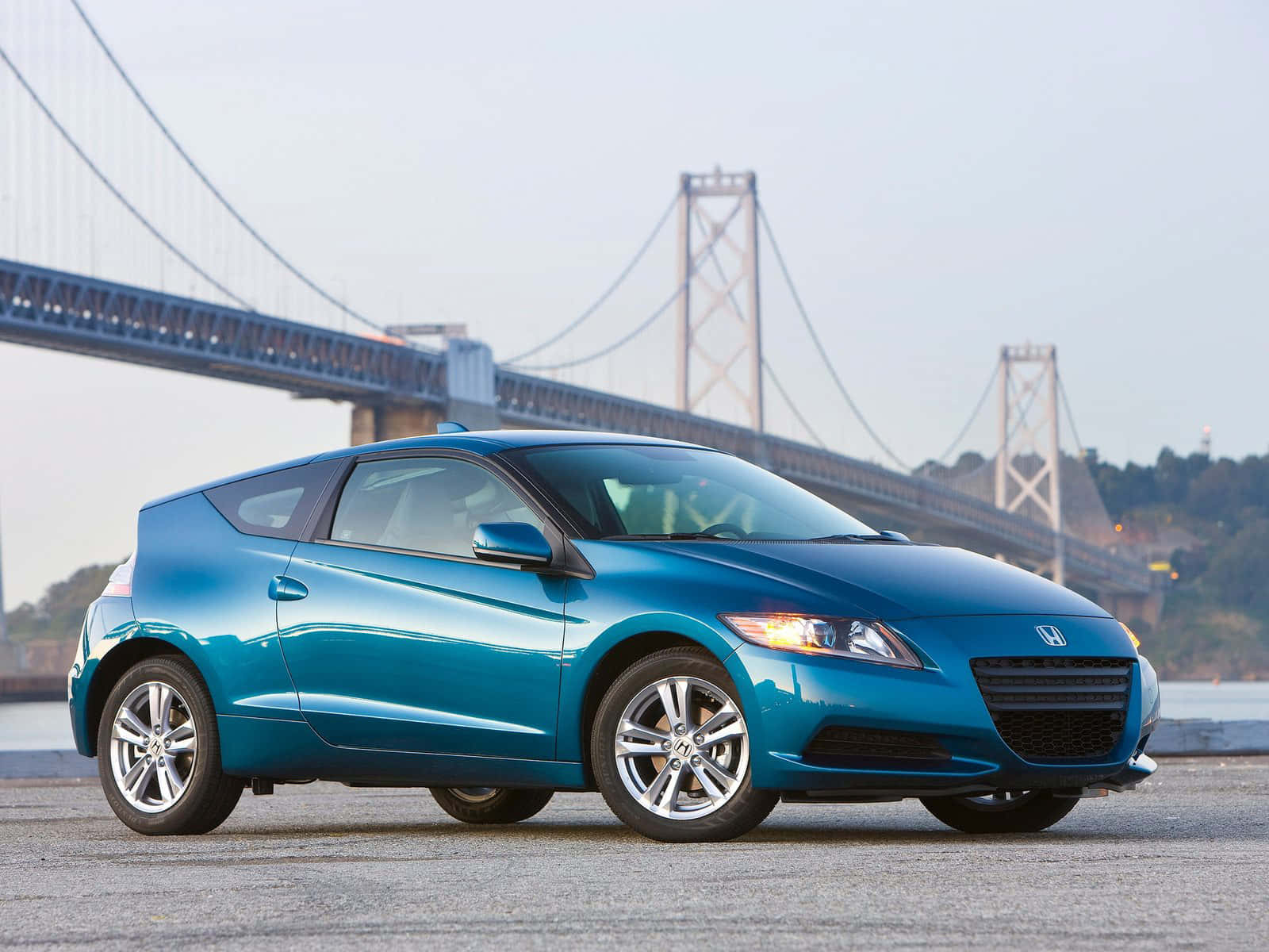 Honda Cr-z 桌布 壁紙 — 一台時尚的青綠色本田CR-Z跑車停放在大型吊橋附近，背景有水域。