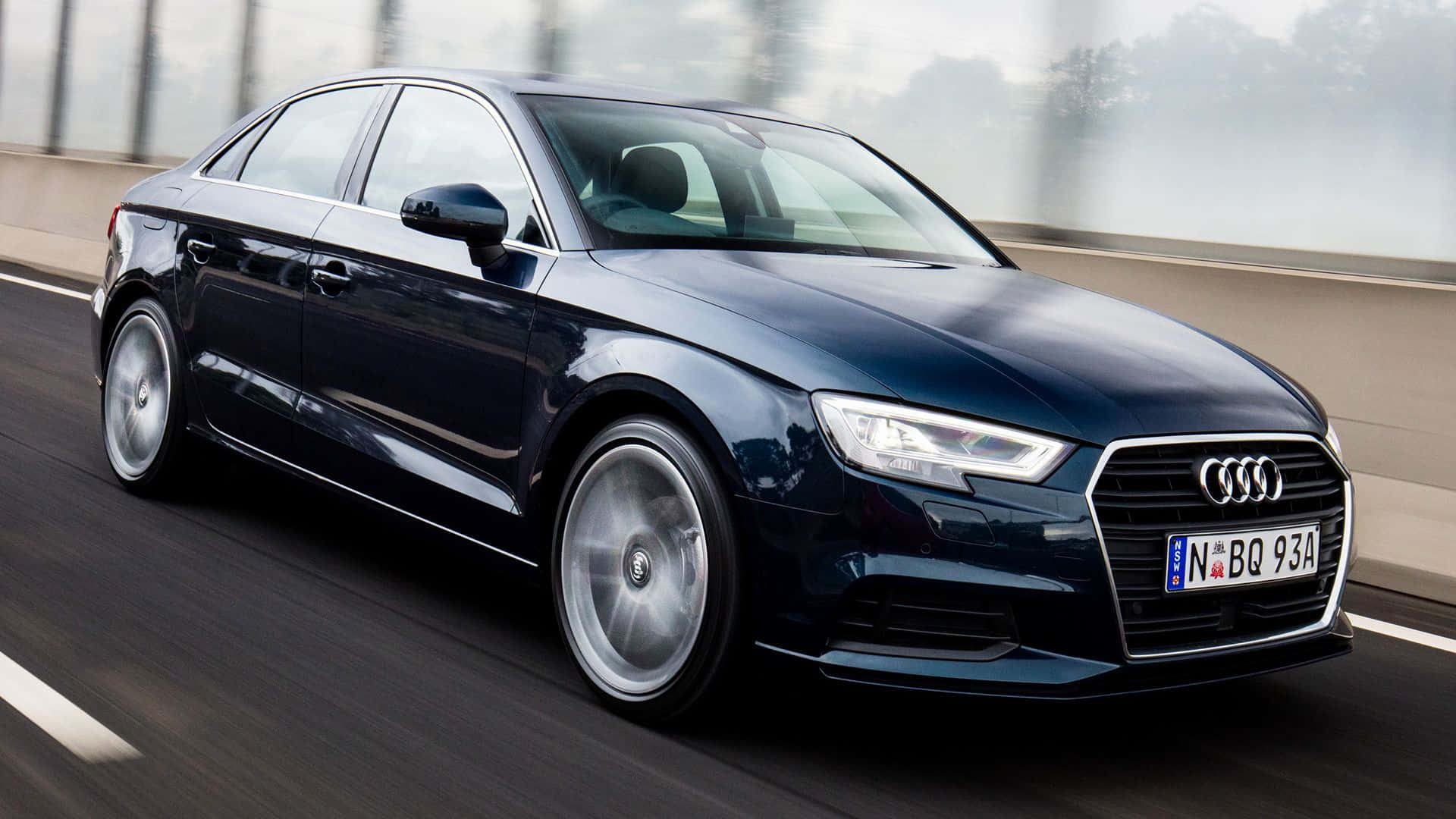 Audi A3 桌布 壁紙 — 一台時尚的深藍色奧迪轎車在模糊的高速公路上疾馳，動態模糊強調了其動態運動。