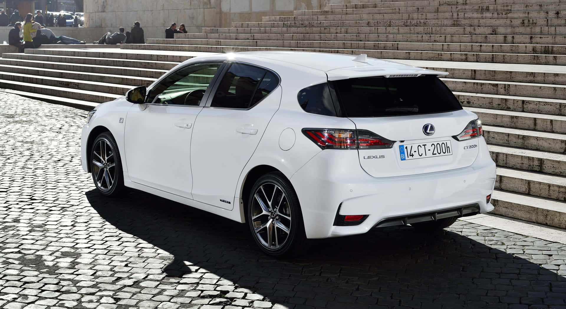 Lexus Ct 200h 桌布 壁紙 — 一台時尚的白色Lexus CT 200h混合動力掀背車停在鵝卵石階梯上，背景中有人在放鬆。