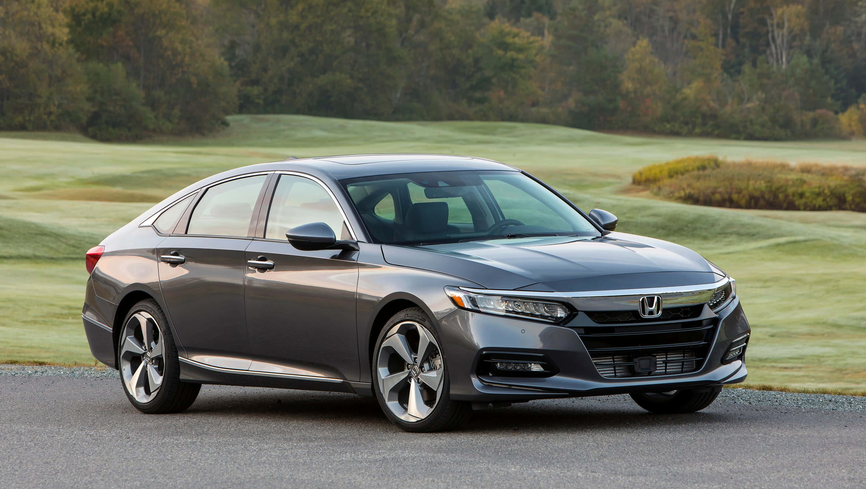Honda Accord 桌布 壁紙 — 一台時尚的灰色本田雅閣轎車停泊在碎石路上，旁邊是修剪整齊的綠色高爾夫球場，背景有秋天的樹木。