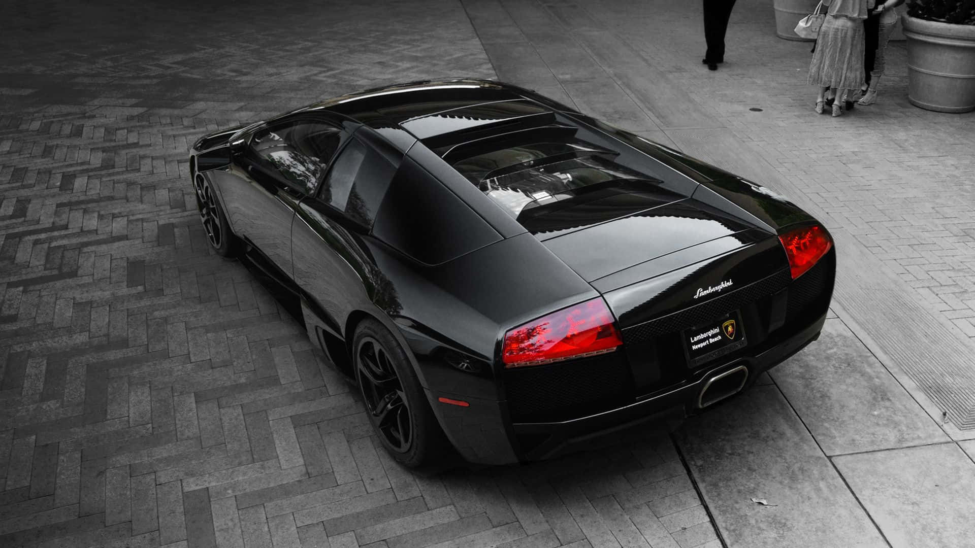 Lamborghini Murciélago 桌布 壁紙 — 一台型格黑色藍寶堅尼 Murciélago 停放在人字形磚砌路面上，紅色尾燈閃爍發光。