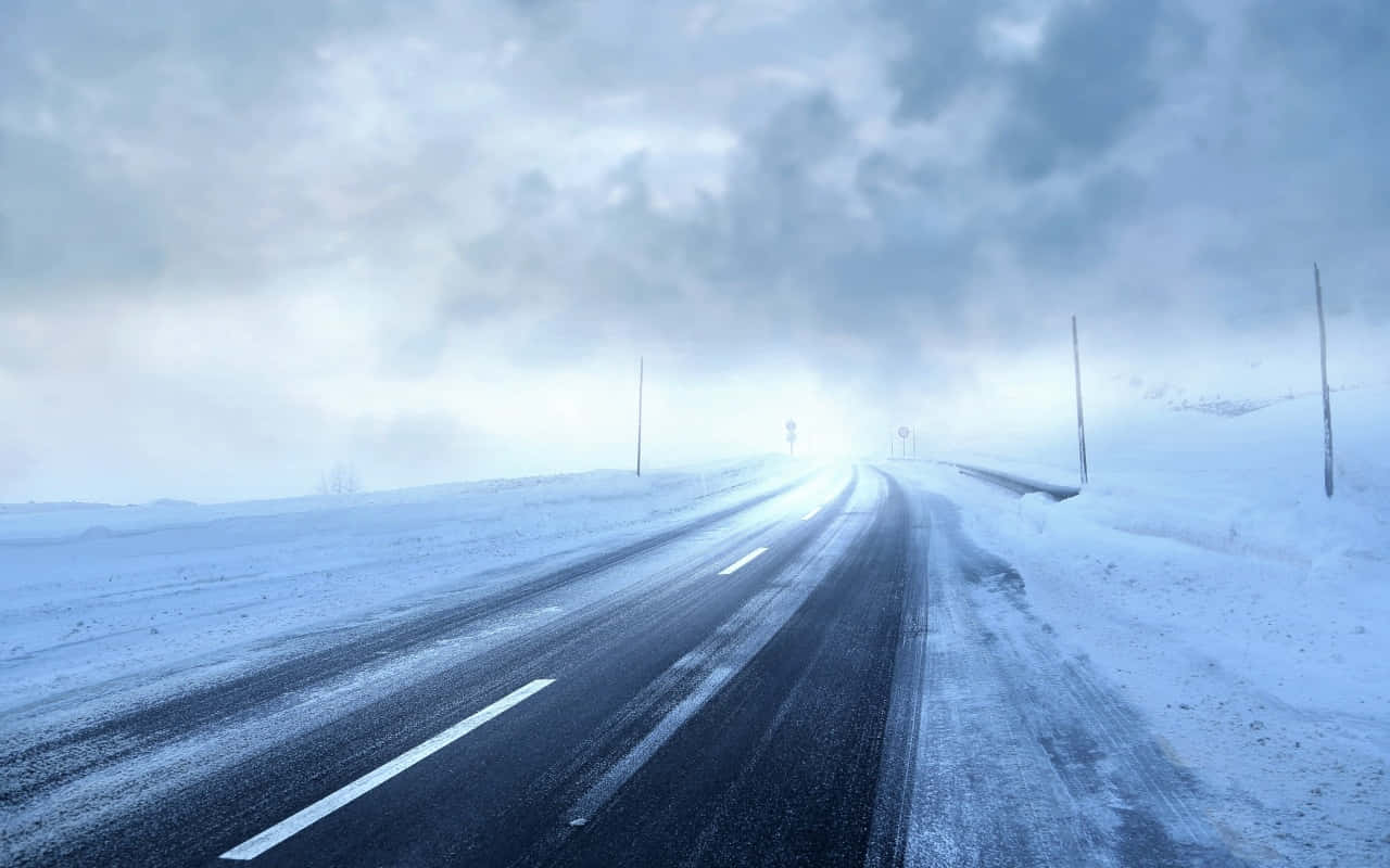  壁紙 — 一條孤獨的積雪道路在陰天之下延伸至霧濛濛的冬季地平線。