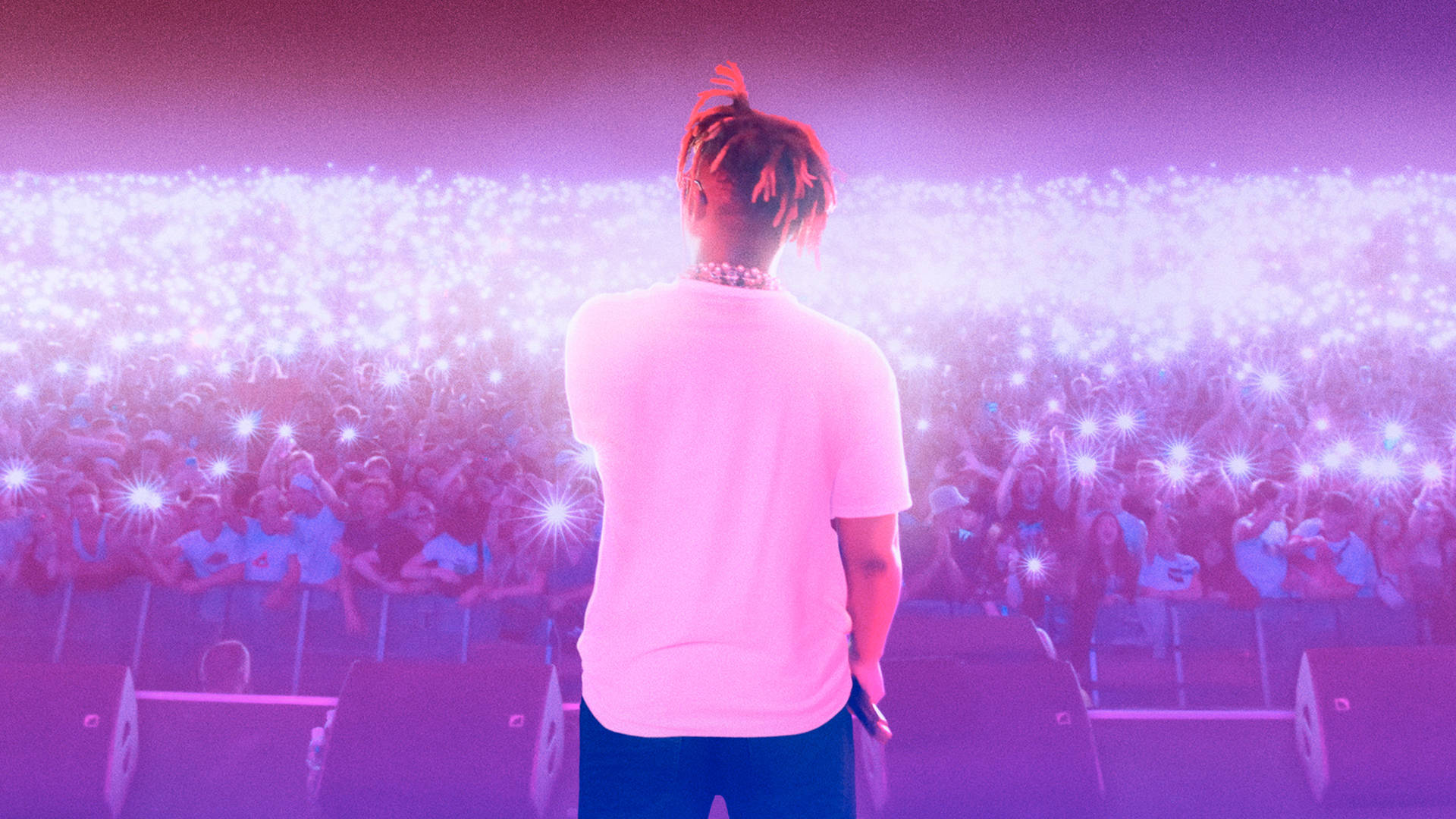 表演者在舞台上，面對著在音樂會中舉起發光手機的觀眾。 — Juice Wrld 壁紙