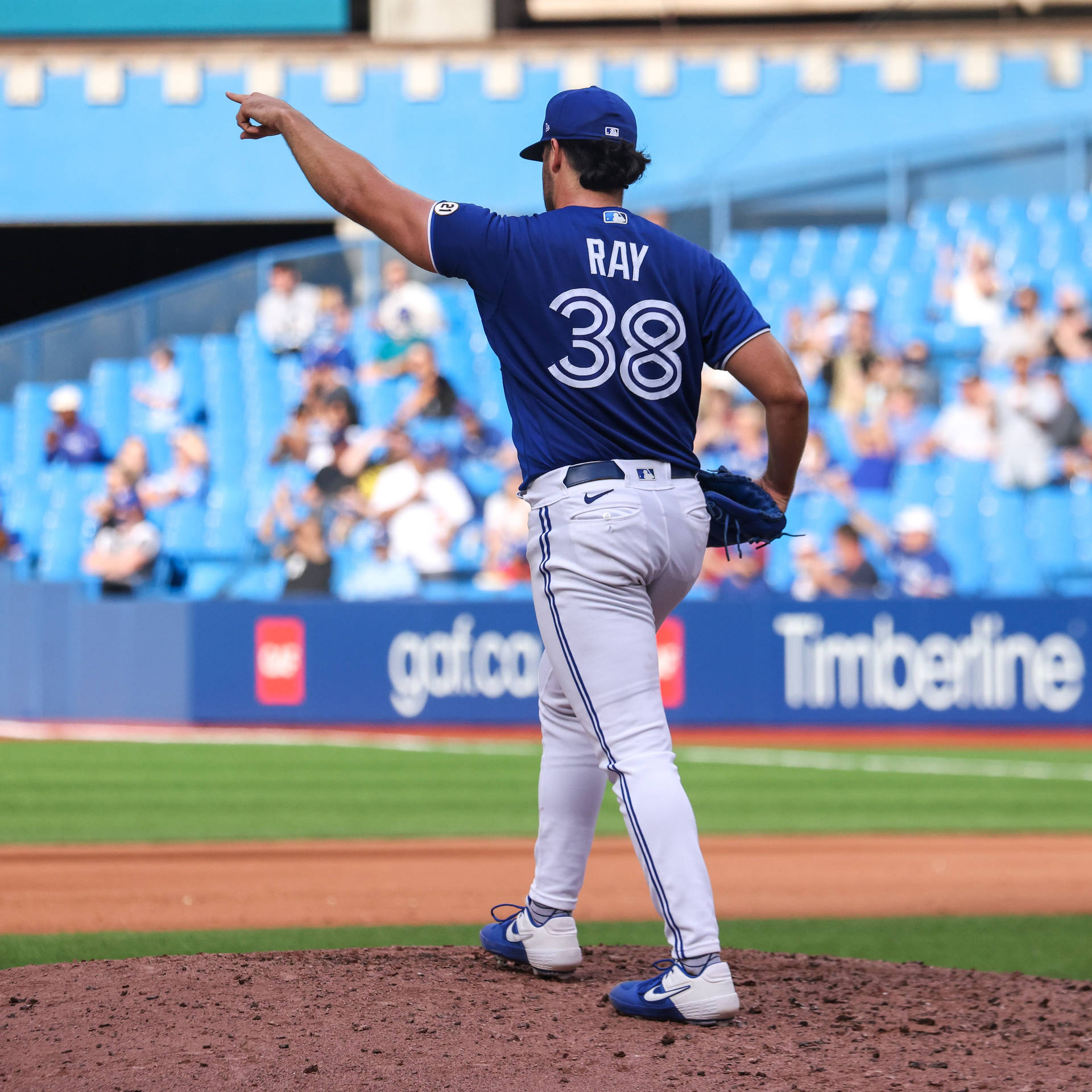 棒球投手在投手丘上指向，背景有觀眾的日間比賽。 — MLB 壁紙