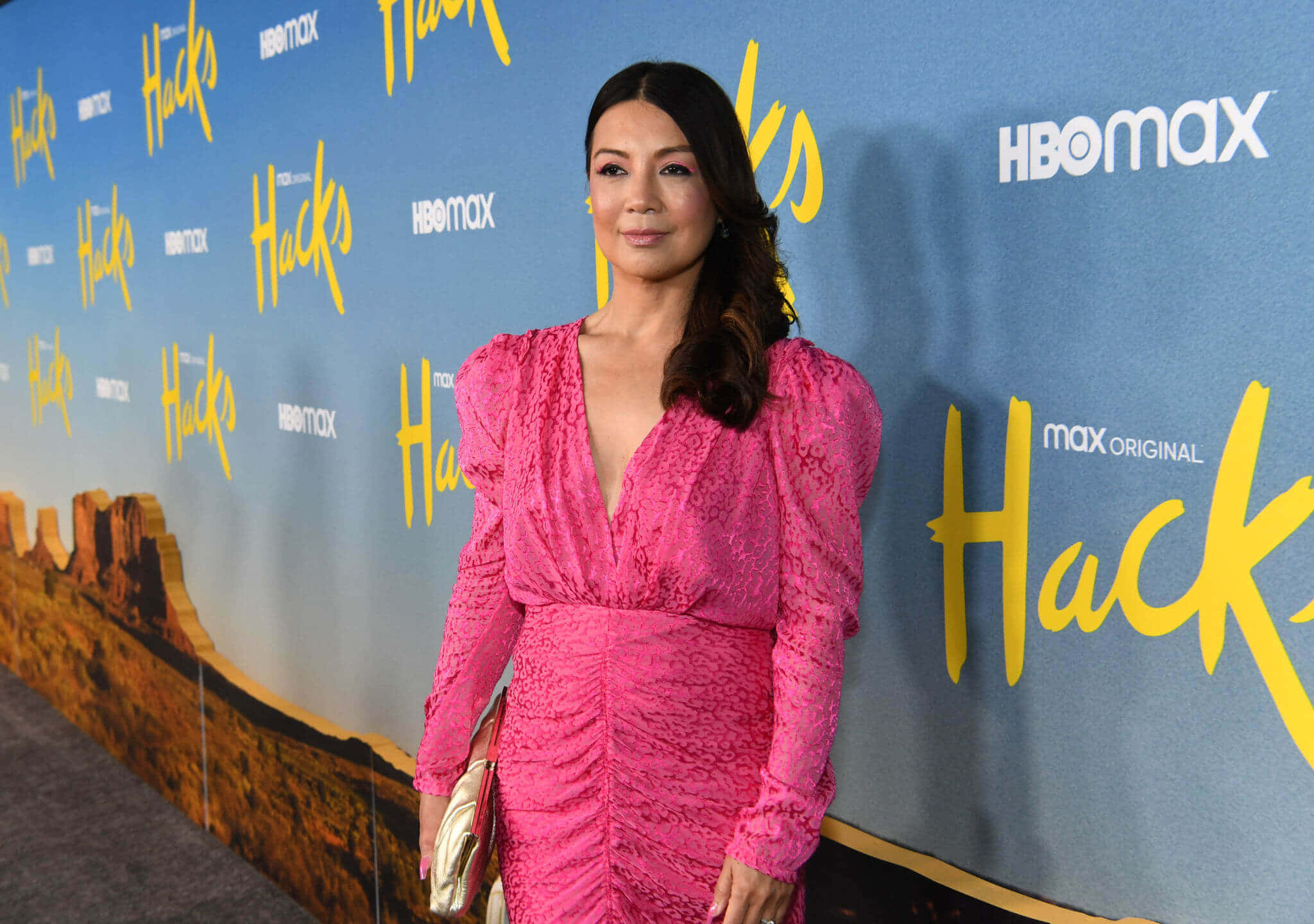 Ming Na Wen 桌布 壁紙 — 一位穿著鮮豔粉紅色蕾絲裙的女性在「Hacks」HBO Max活動中自信地擺姿勢，背景是沙漠峽谷。