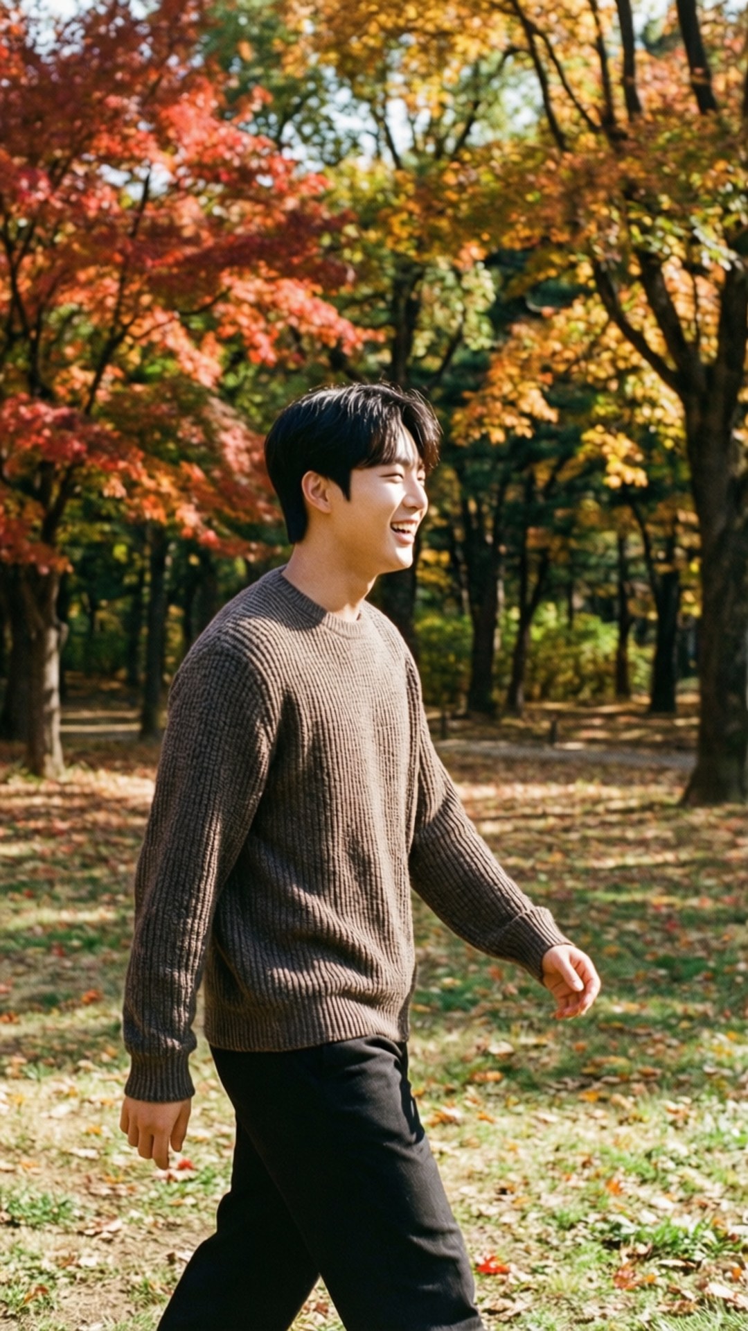 Autumn Stroll 壁紙 — 一位穿著棕色毛衣的年輕男子在陽光明媚的秋日森林中愉快地行走，周圍是鮮紅和橙色的樹葉。