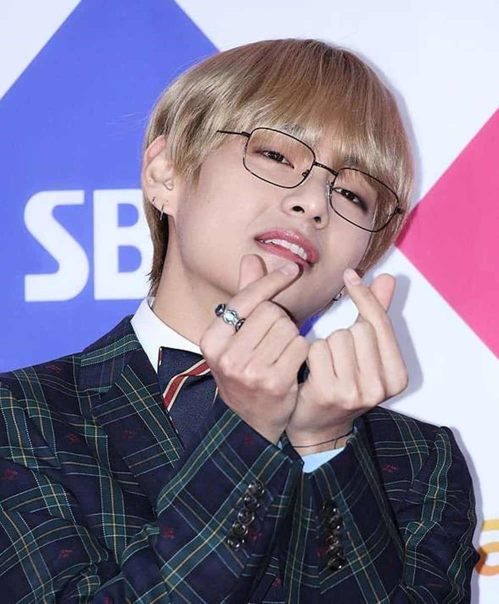 年輕男子穿著格紋西裝在活動中做出心形手勢 — Bts 壁紙