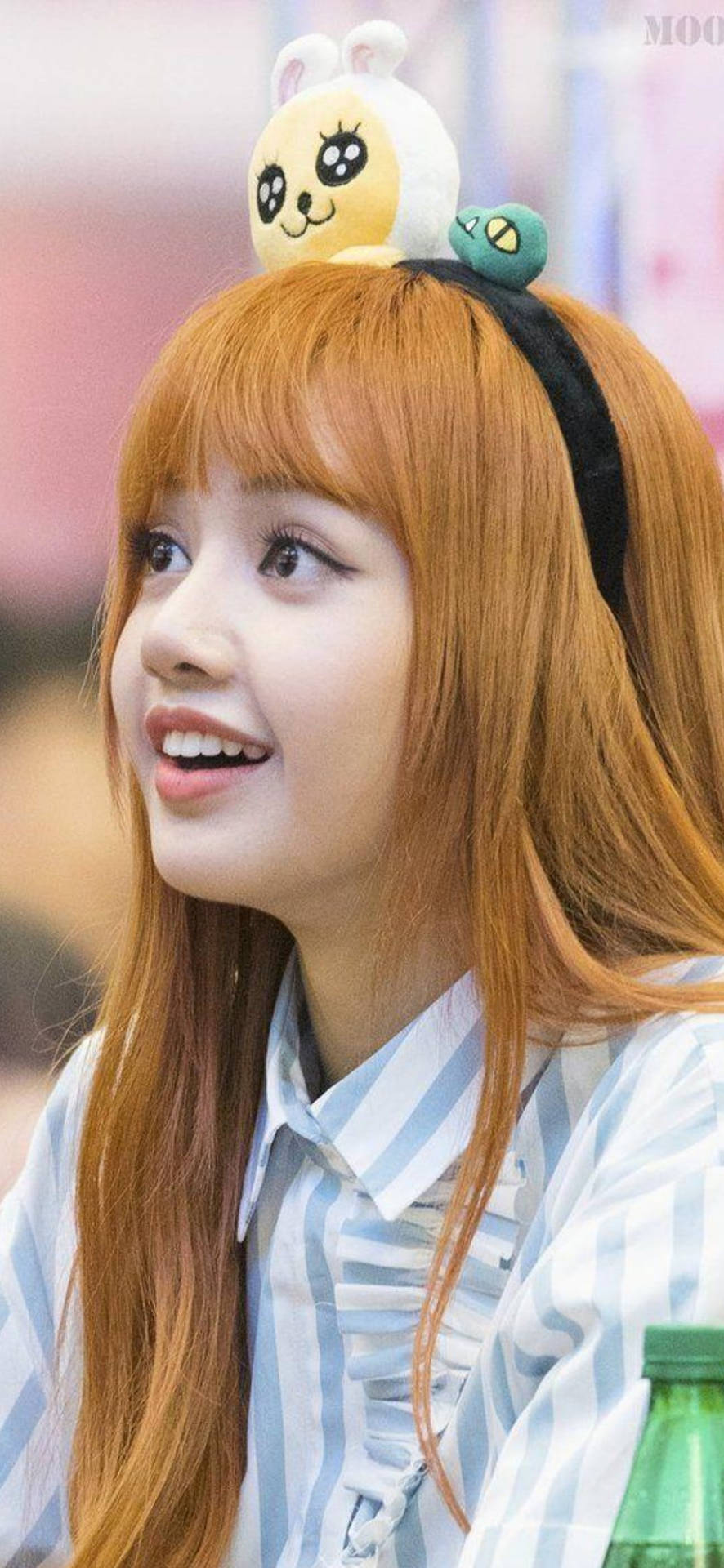橙色頭髮的年輕女性戴著毛絨兔頭帶微笑。 — Blackpink 壁紙