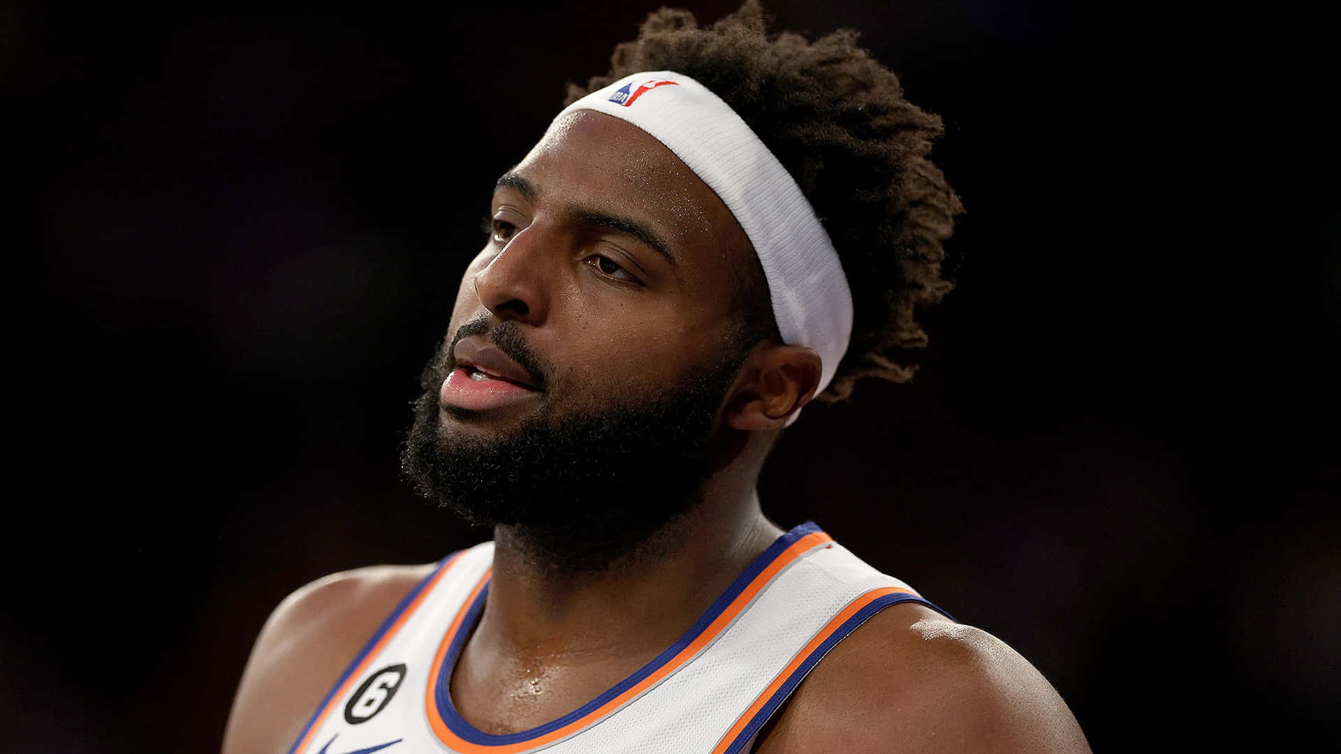 留鬍鬚的籃球運動員特寫，戴著頭帶和球隊球衣。 — NBA 壁紙