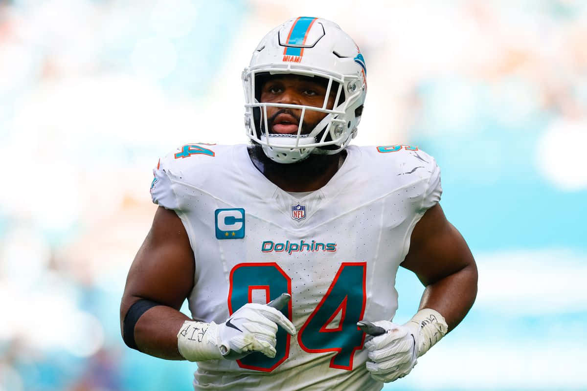  壁紙 — 一位邁阿密海豚隊NFL球員身穿白色84號球衣，在明亮的球場上專注地奔跑。