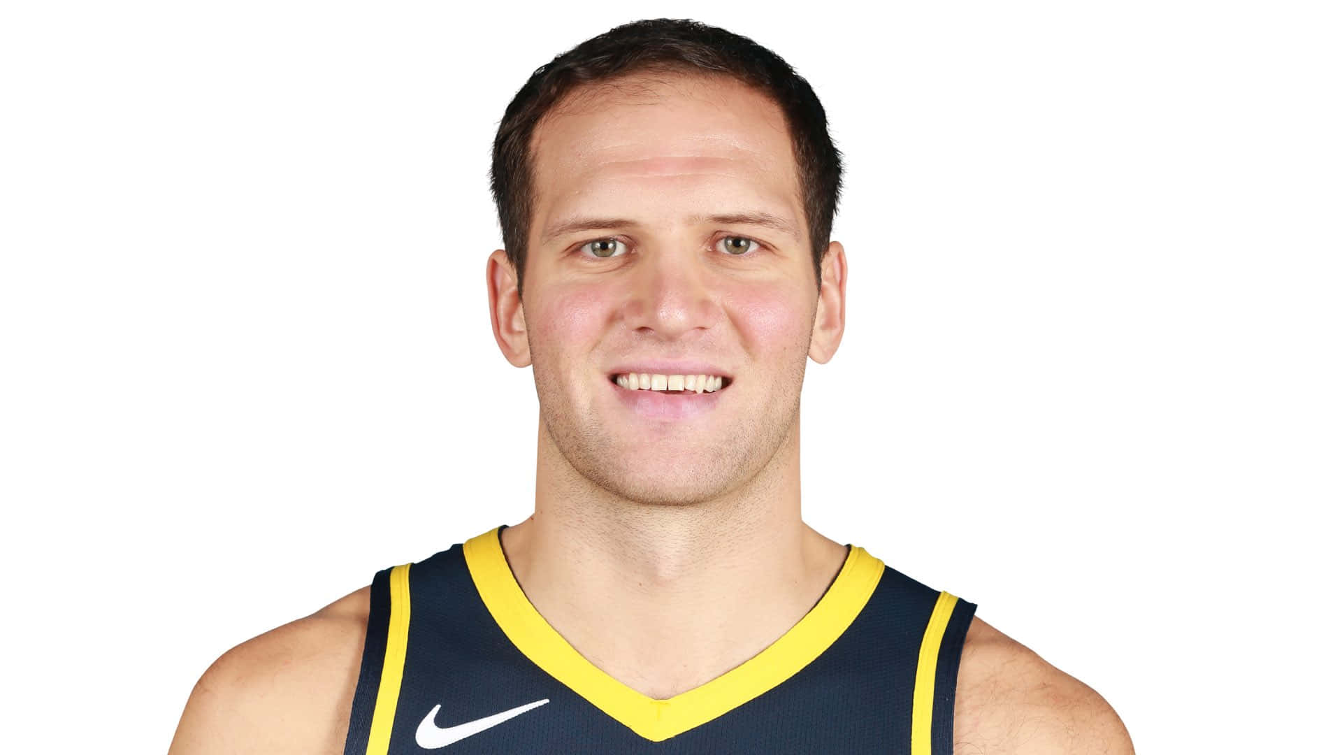 身穿海軍藍和黃色球衣的籃球運動員對著鏡頭微笑。 — NBA 壁紙
