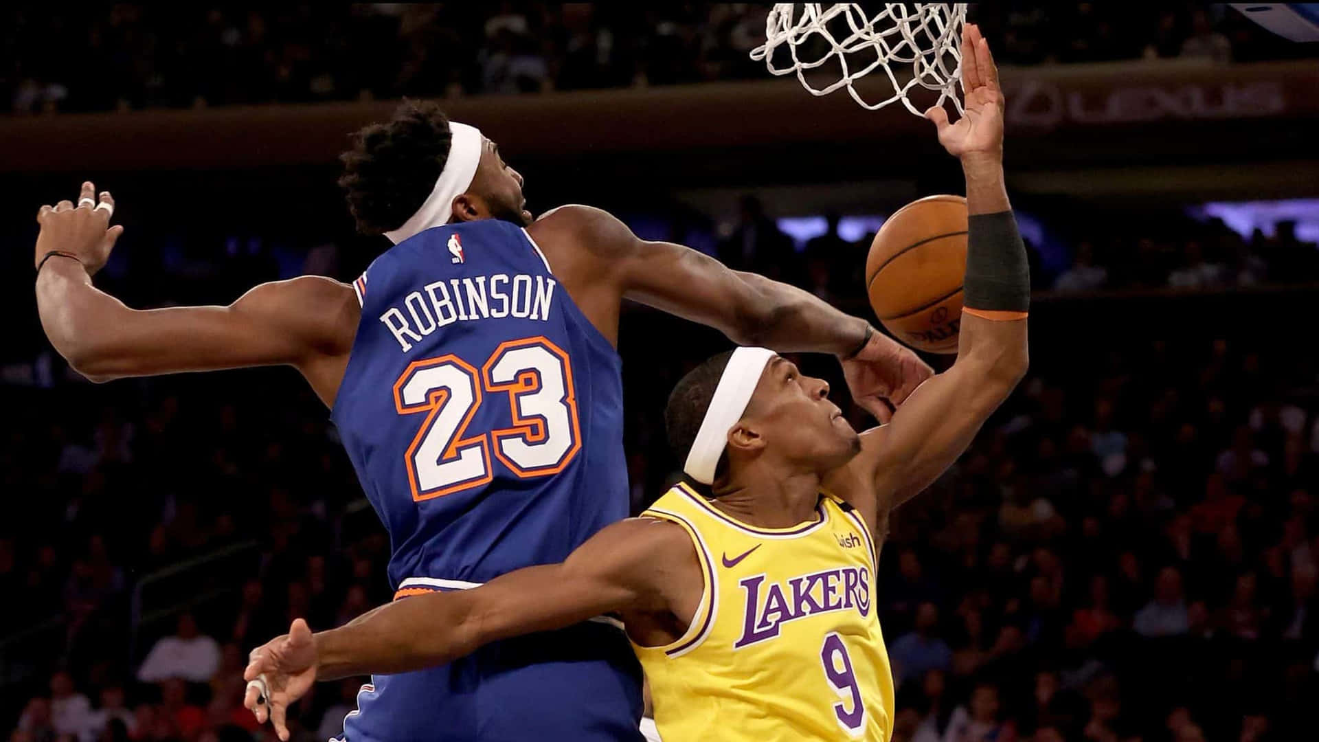 兩名籃球運動員在擠滿觀眾的場館內於籃框附近爭奪投籃機會。 — NBA 壁紙
