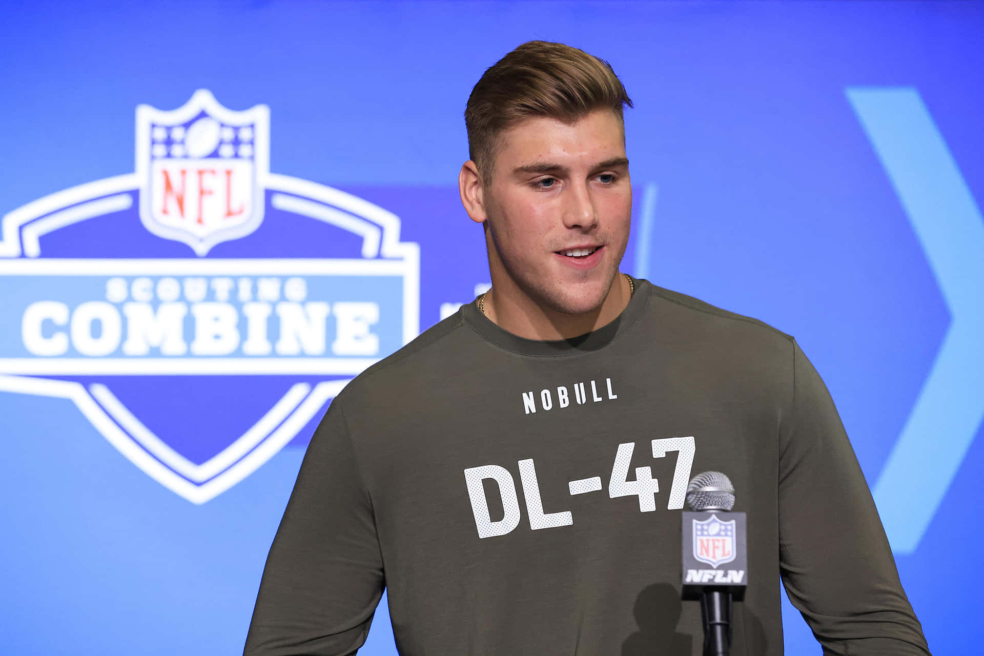  壁紙 — 一位身穿灰色 'DL-47' 球衣的年輕NFL球員在NFL選秀聯合試訓記者會上發言。