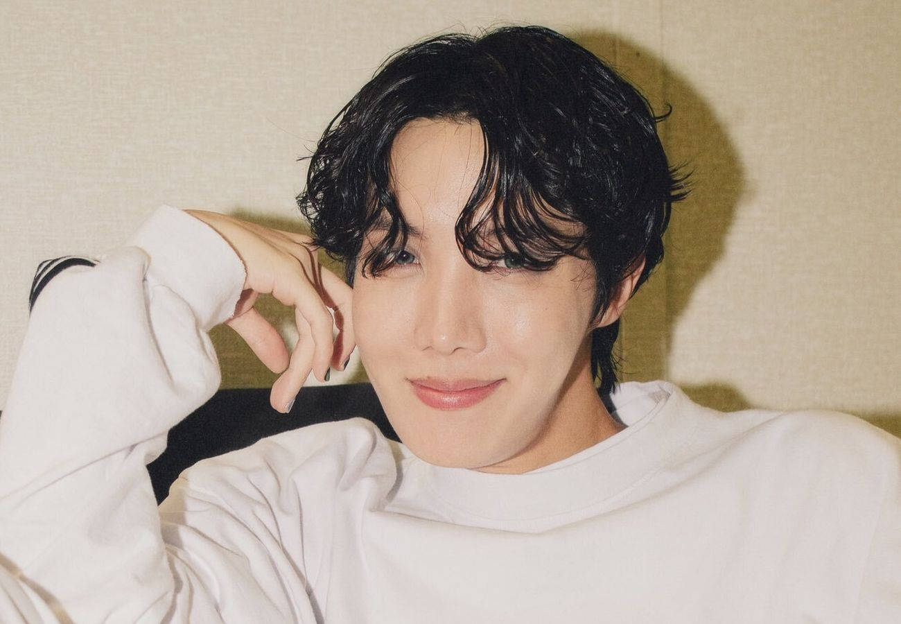 深色頭髮的年輕男子，身穿白色衛衣，將手放在臉旁微笑。 — Bts 壁紙