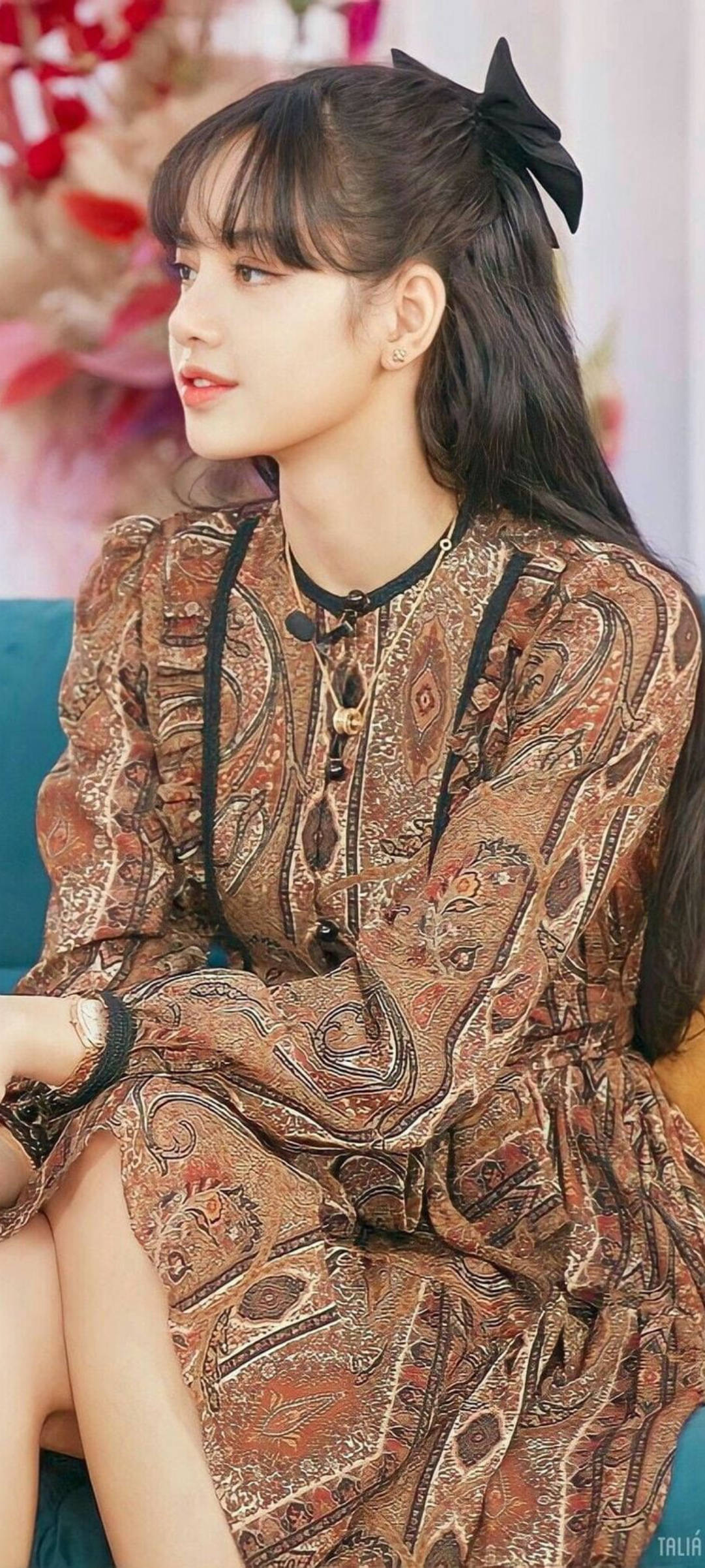 年輕女性身穿圖案連衣裙、戴黑色蝴蝶結坐在藍綠色沙發上 — Blackpink 壁紙