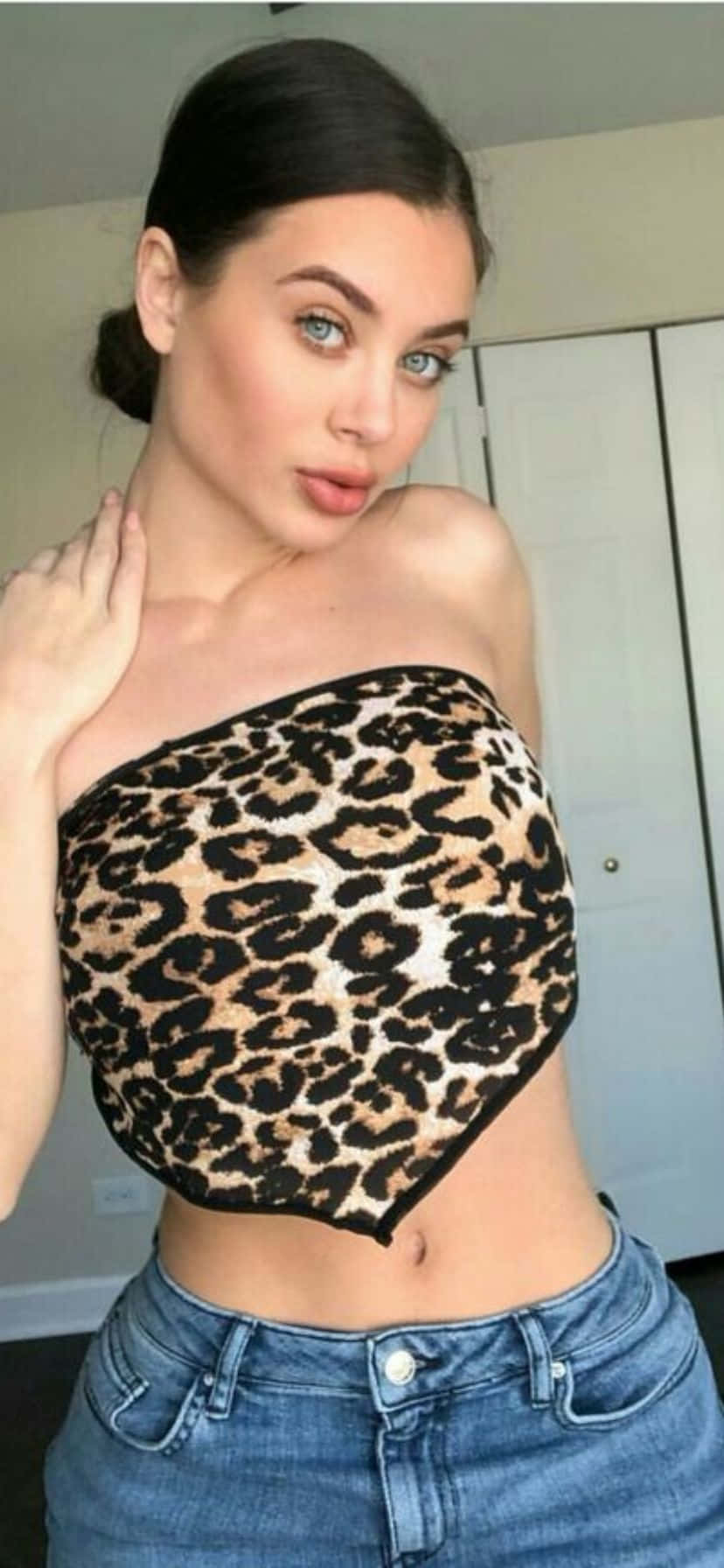  壁紙 — 一位深色頭髮、藍色眼睛的女性穿著豹紋露臍上衣和牛仔褲，在室內擺姿勢。