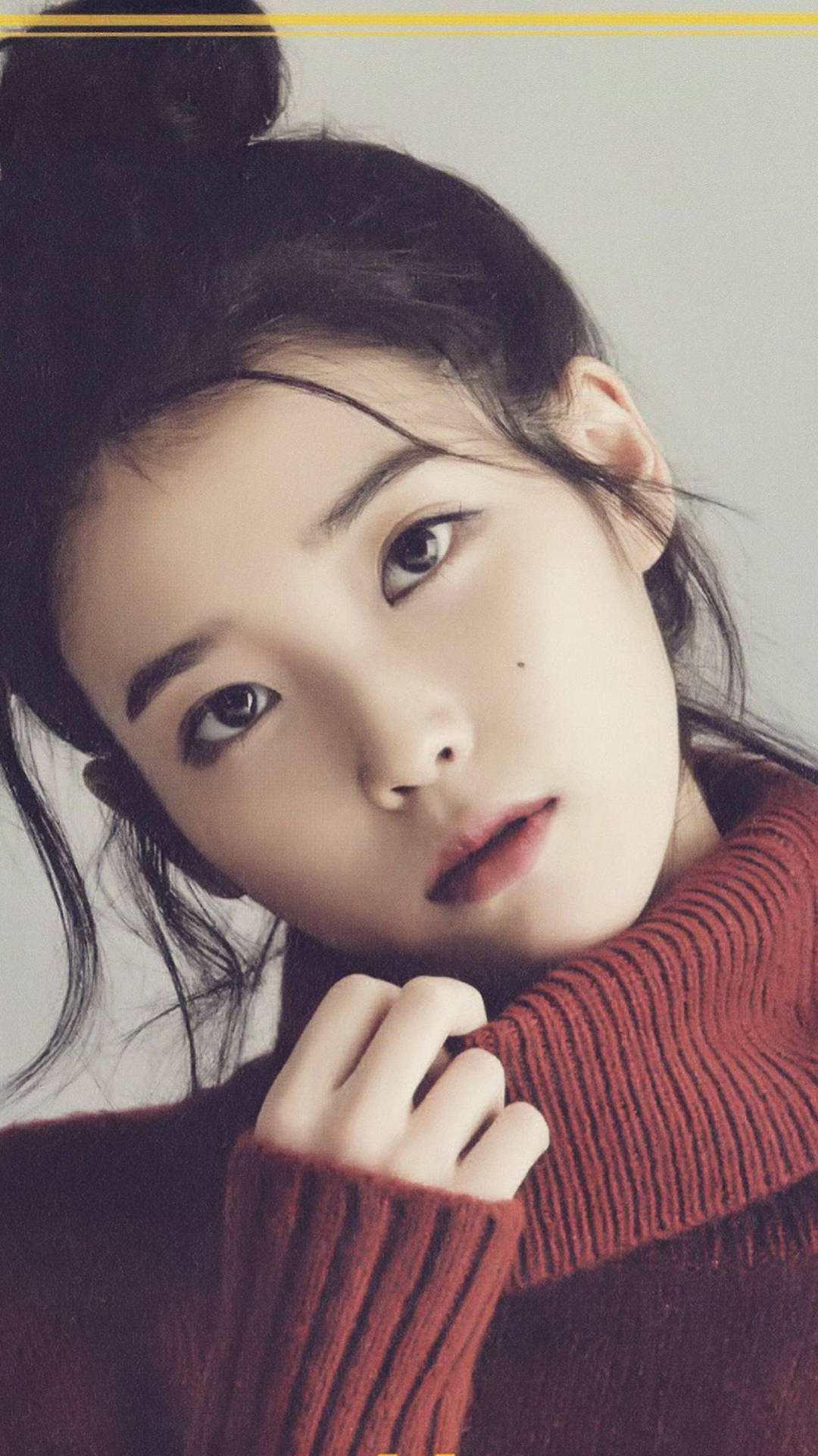 身穿紅色毛衣的年輕女性，溫柔地將下巴擱在毛衣上。 — K Pop 壁紙