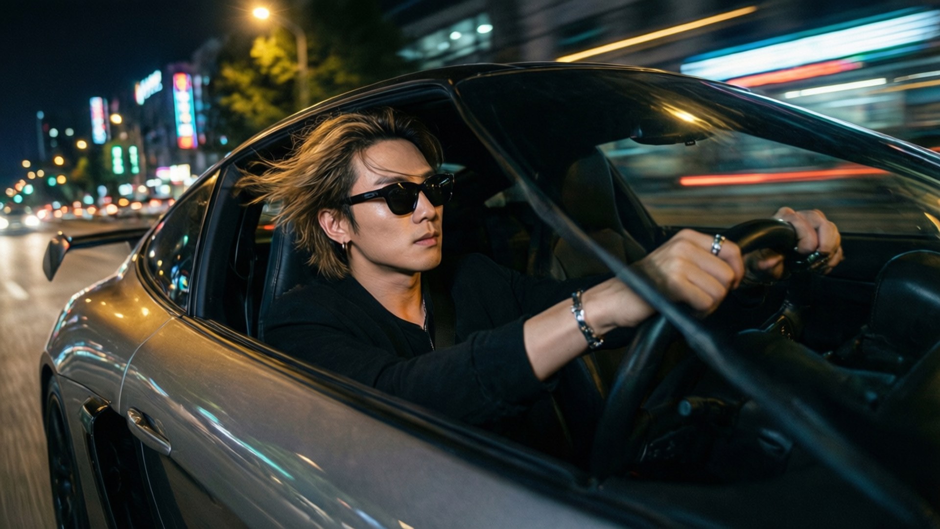 Night Drive Jackson Wang 壁紙 — 一位時尚男士，頭髮被風吹起，戴著太陽眼鏡，在夜晚駕駛一輛銀色流線型跑車穿過霓虹燈閃爍的城市。