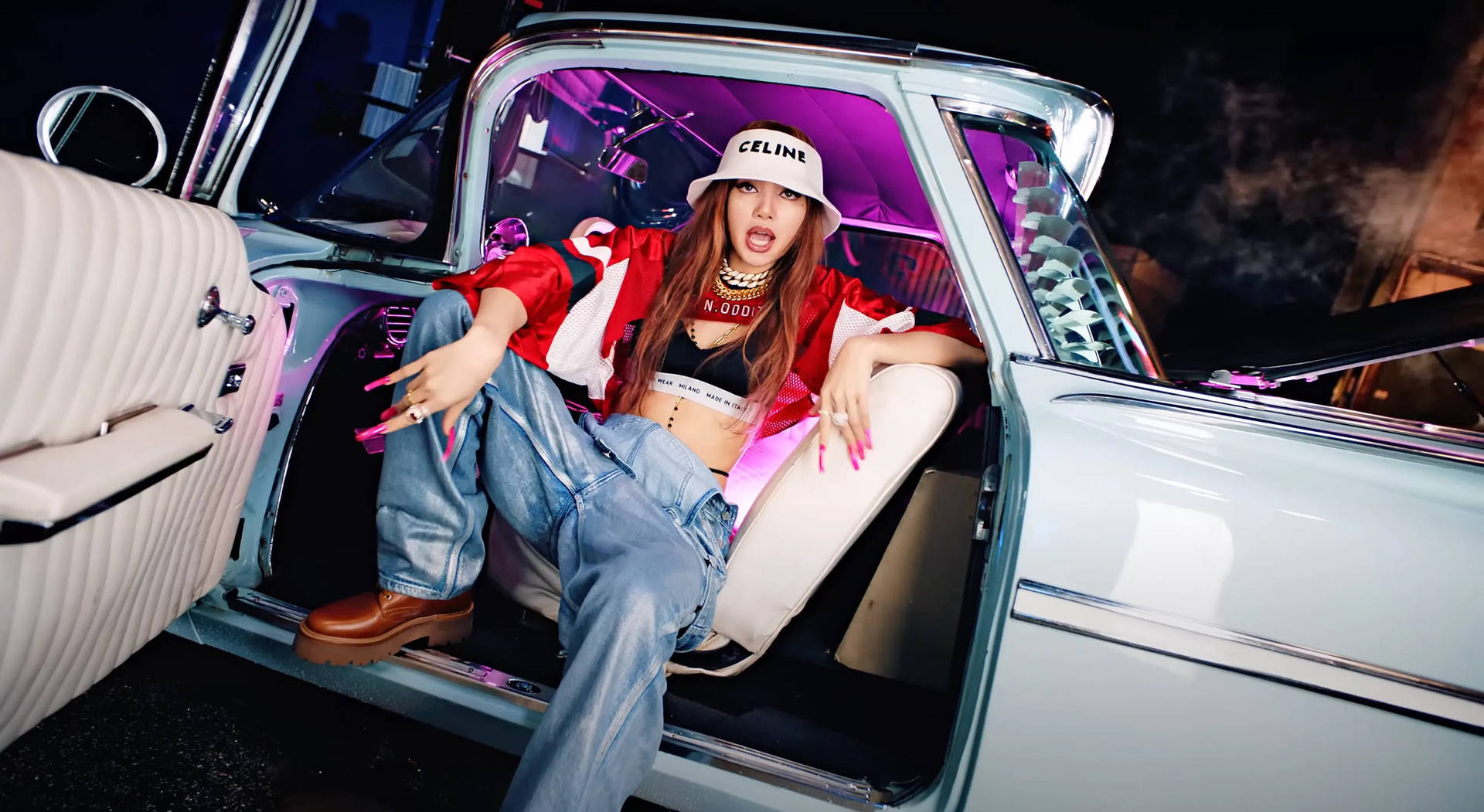 一位穿著街頭服飾的女性在夜間霓虹燈下於復古車中擺姿勢。 — Blackpink 壁紙
