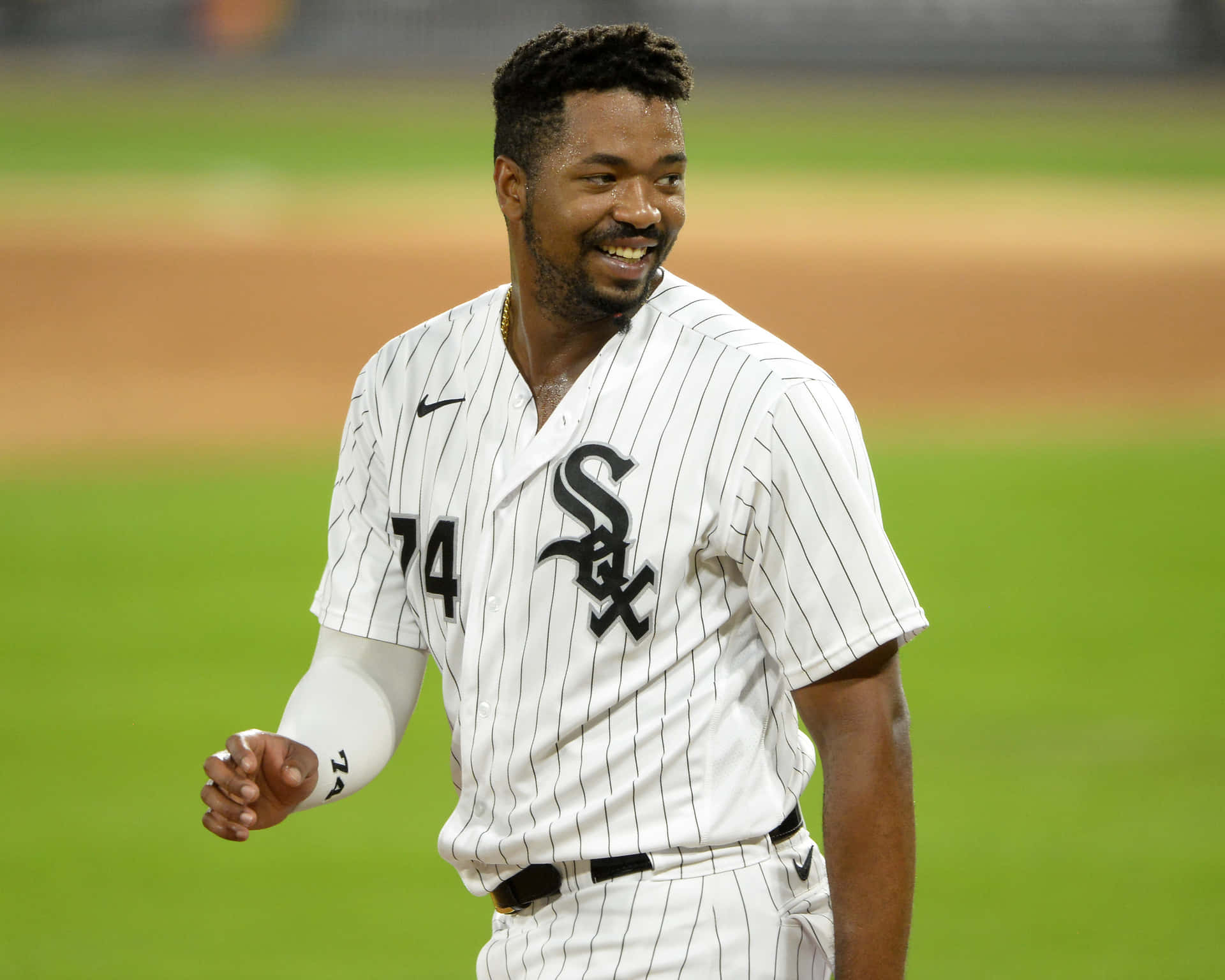 身穿白色細條紋制服的棒球運動員在夜間綠色場地上微笑。 — MLB 壁紙