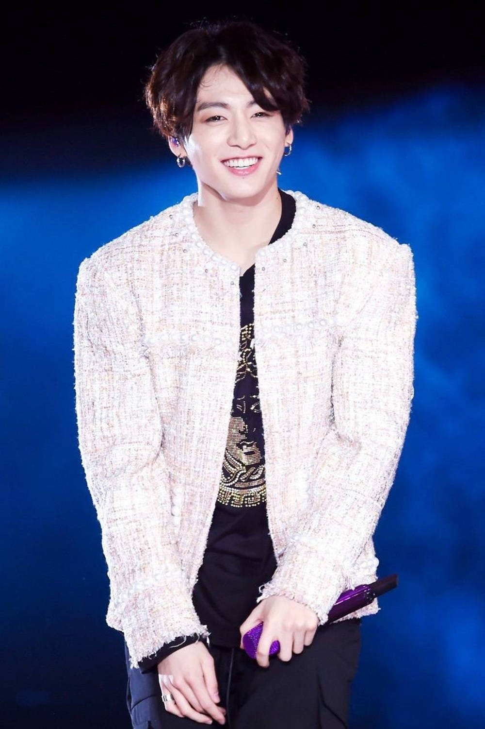 K-pop表演者穿著白色外套和黑色襯衫，在舞台上微笑拿著紫色麥克風。 — Bts 壁紙