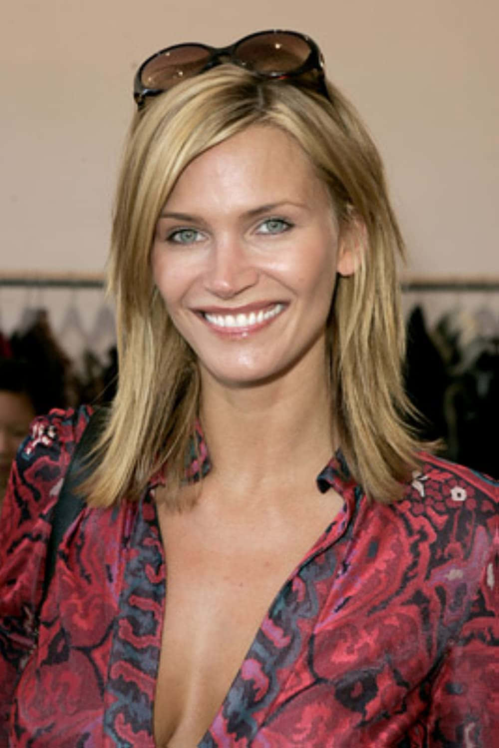 Natasha Henstridge 桌布 壁紙 — 一位微笑的金髮女性，太陽眼鏡架在頭上，穿著鮮豔的紅黑圖案襯衫。