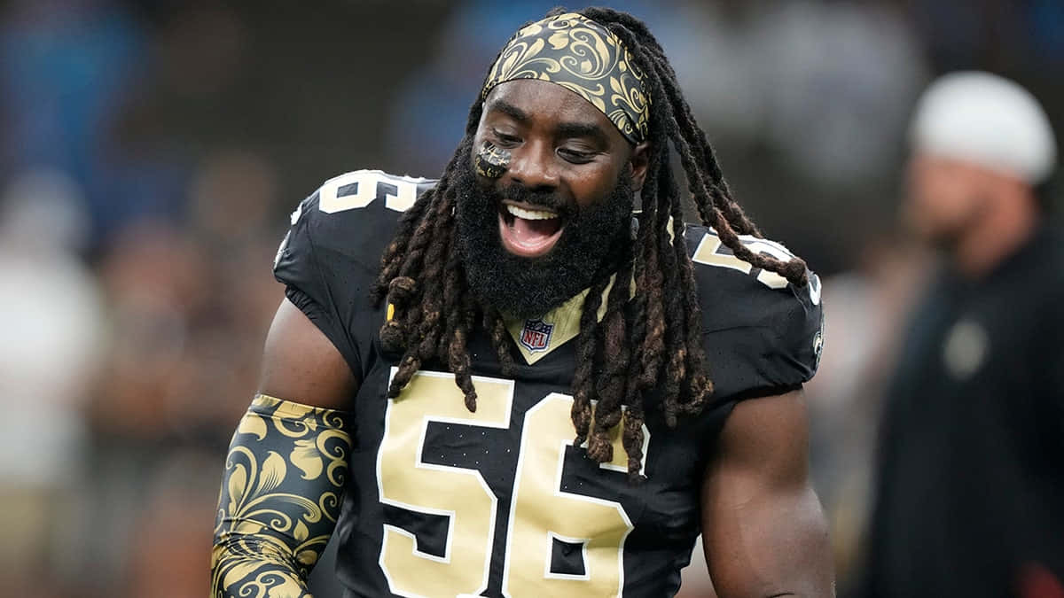  壁紙 — 一位微笑的NFL球員，身穿黑金色制服，號碼56，頭帶和手臂上有華麗圖案。