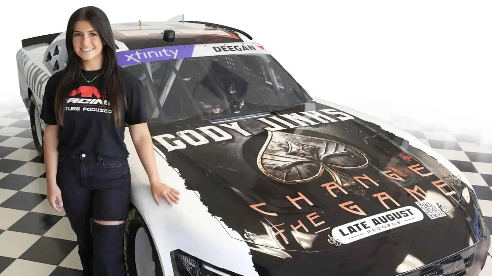  壁紙 — 一位微笑的女性站在黑白賽車旁，賽車上有 'CODY JINKS' 和 'CHANGE THE GAME' 圖案，地面是棋盤格。