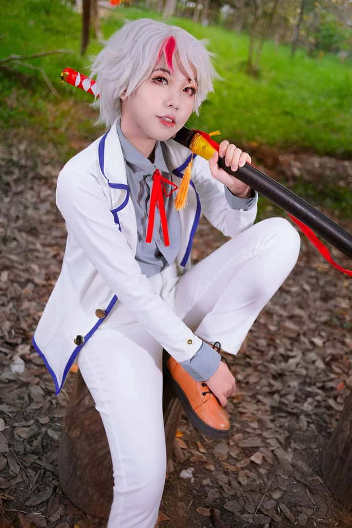 Towa Higurashi 桌布 壁紙 — 一位銀髮帶紅色挑染的cosplayer穿著白色藍邊服裝，手持法杖，在戶外蹲著。