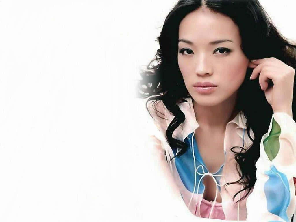 Shu Qi 桌布 壁紙 — 一位擁有深色波浪長髮、身穿彩色圖案襯衫的女性，在純白背景下直視鏡頭。