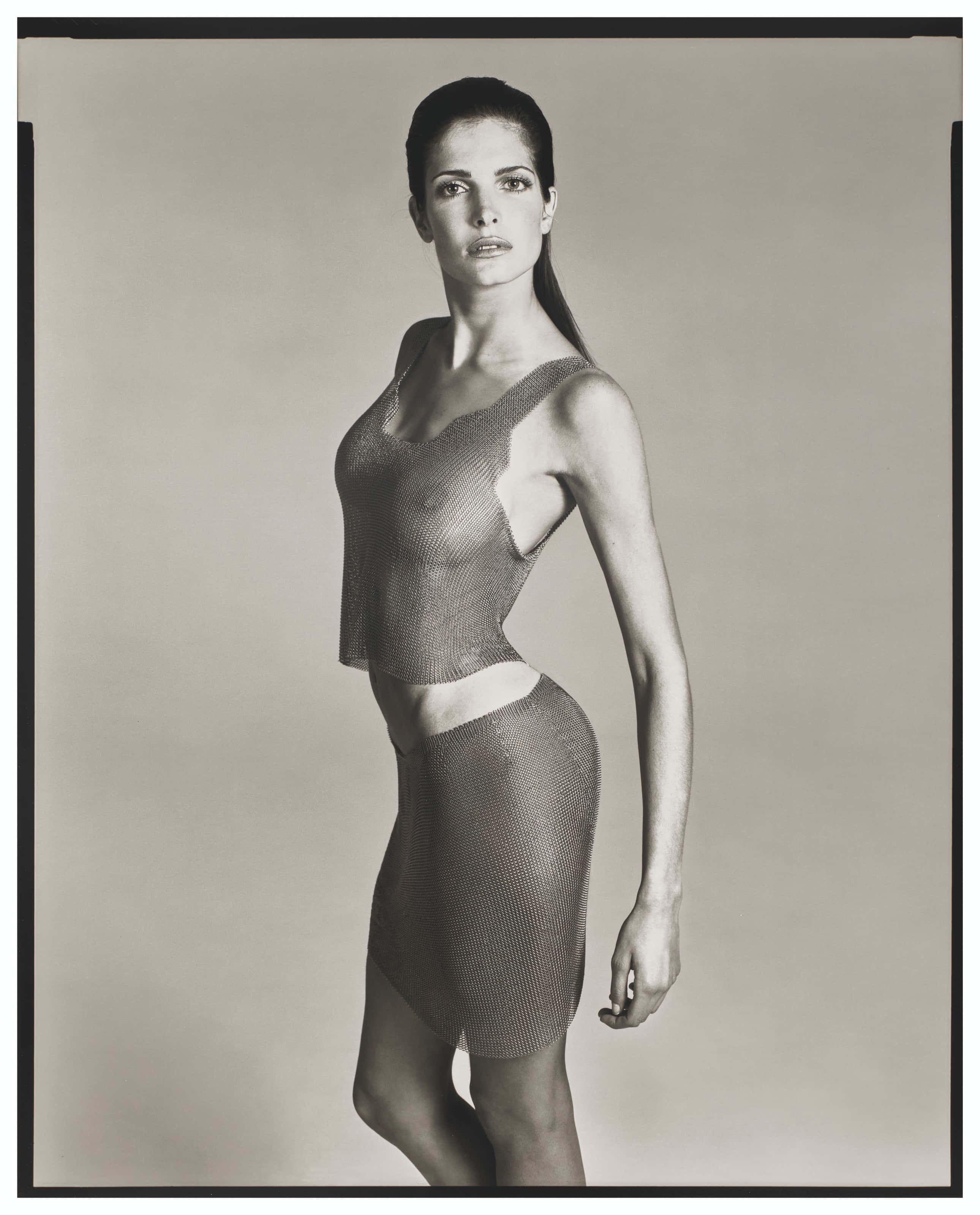 Stephanie Seymour 桌布 壁紙 — 一位優雅的女士穿著質感網眼服裝，在簡約的攝影棚背景前，呈現出引人注目的黑白肖像。