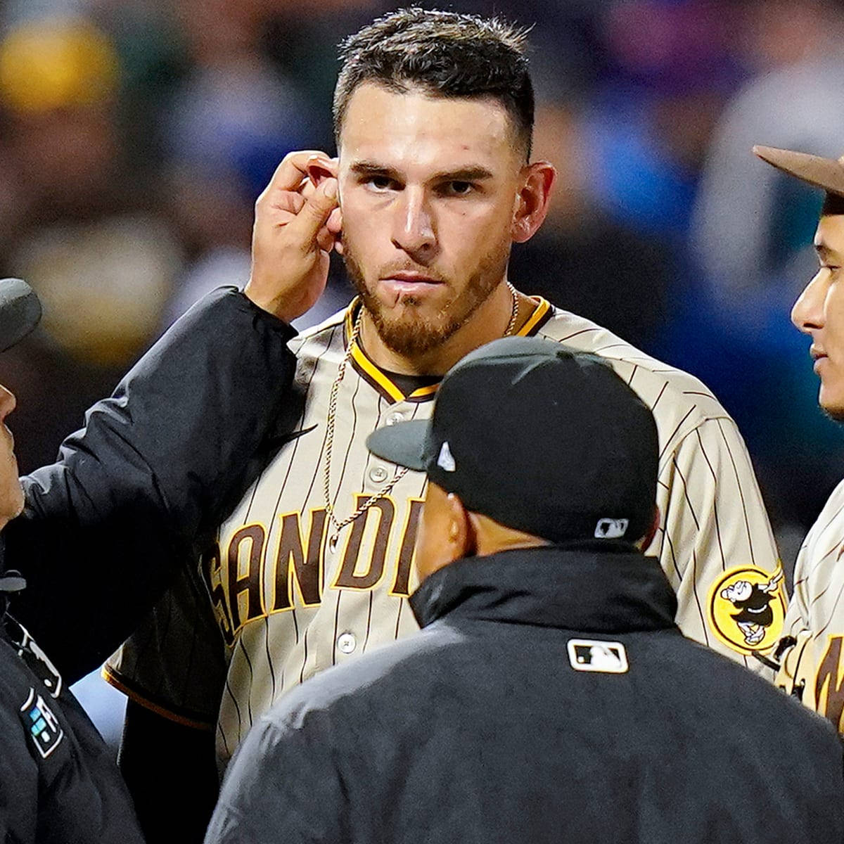棒球運動員在夜間比賽中調整耳機，隊友在附近。 — MLB 壁紙