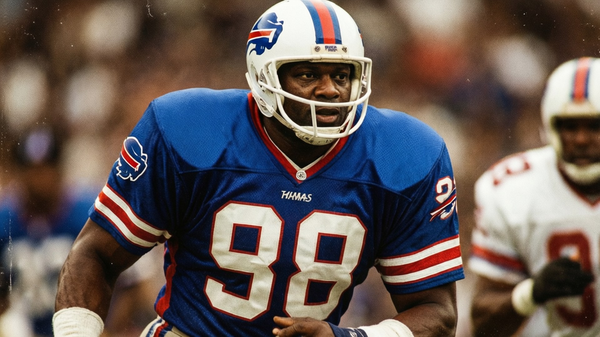 Thurman Thomas Retro 壁紙 — 一位專注的布法羅比爾隊美式足球員，身穿藍色98號球衣，在比賽中準備就緒站在場上。