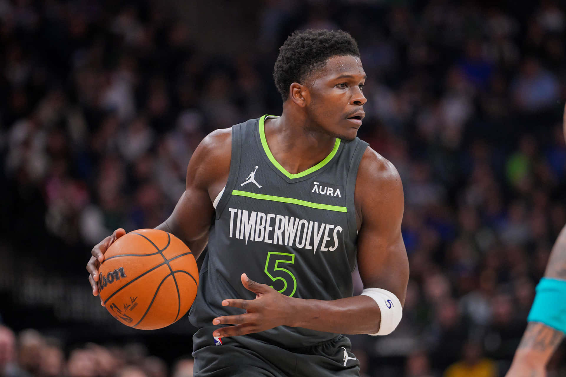  壁紙 — 一位專注的籃球運動員穿著灰色 Timberwolves 球衣，在比賽中運著橙色籃球，身後是模糊的人群。