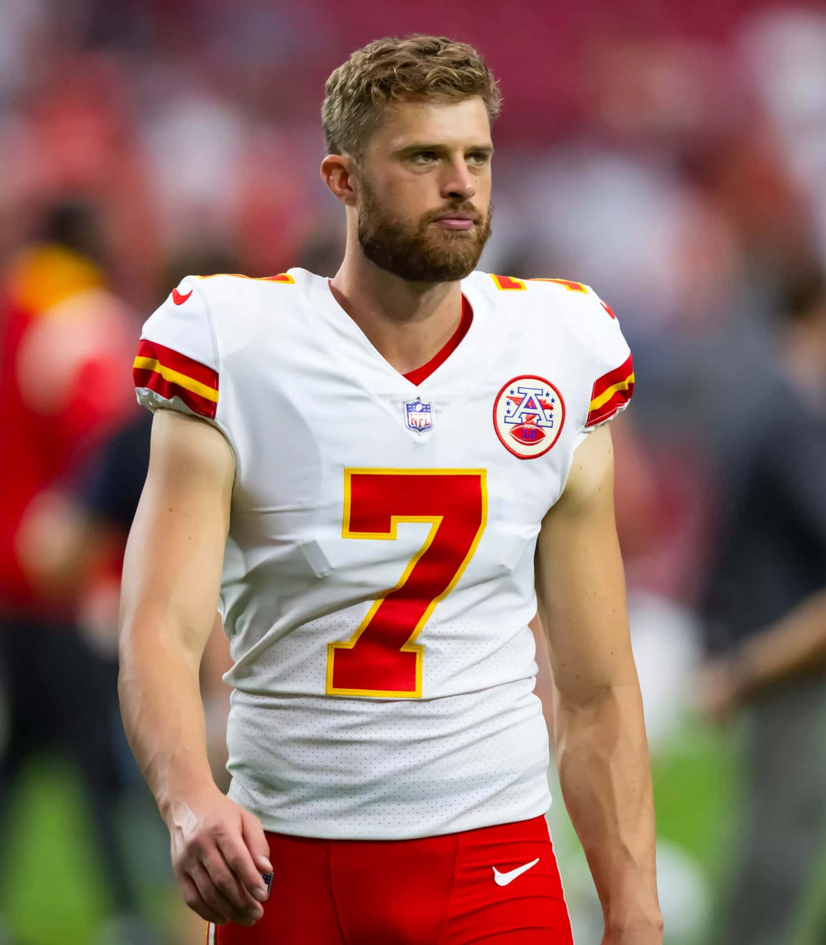  壁紙 — 一位專注的NFL四分衛身穿白色和紅色7號球衣，在比賽期間站在足球場上。