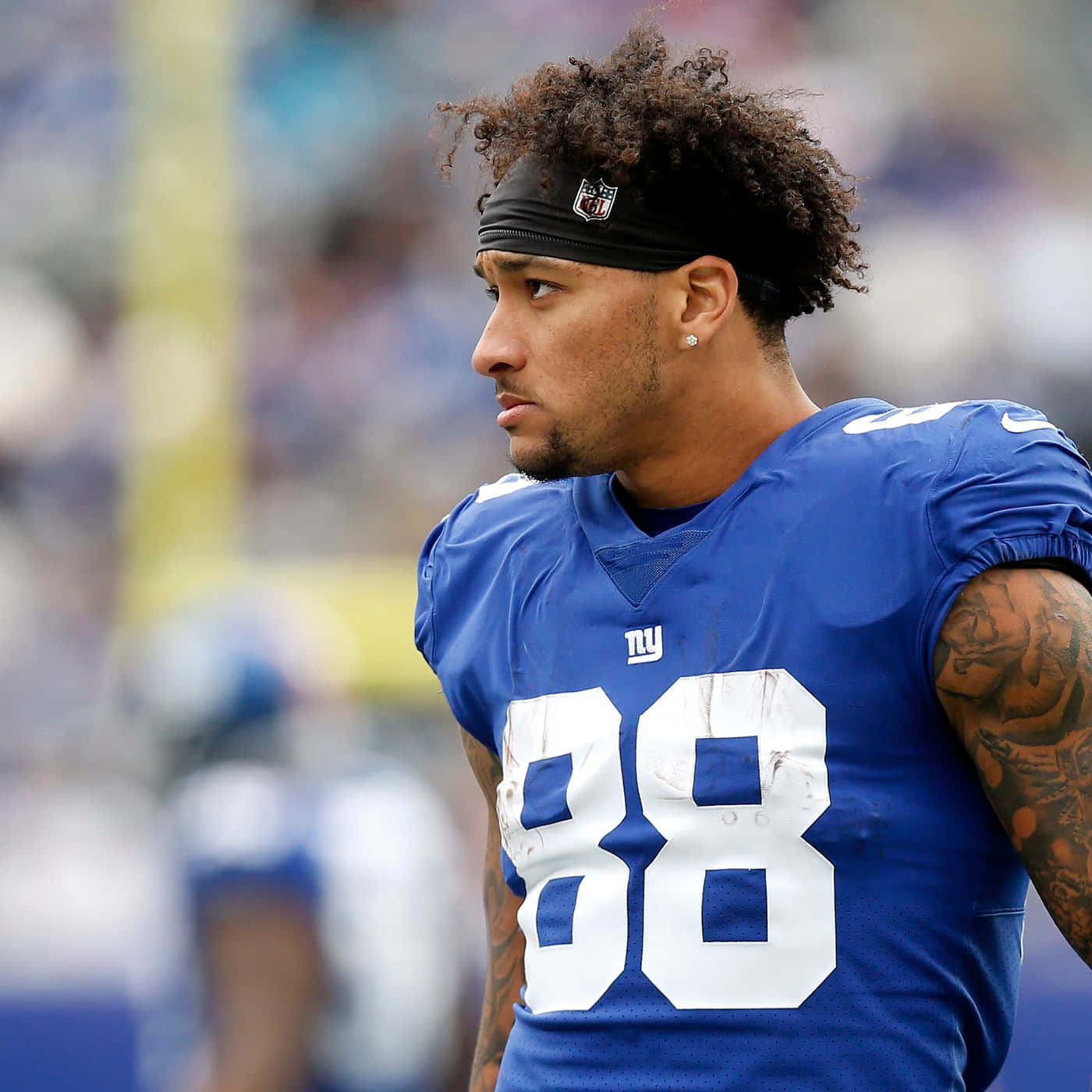  壁紙 — 一位專注的NFL外接手身穿藍色球衣，號碼88，在比賽中站在球場上。