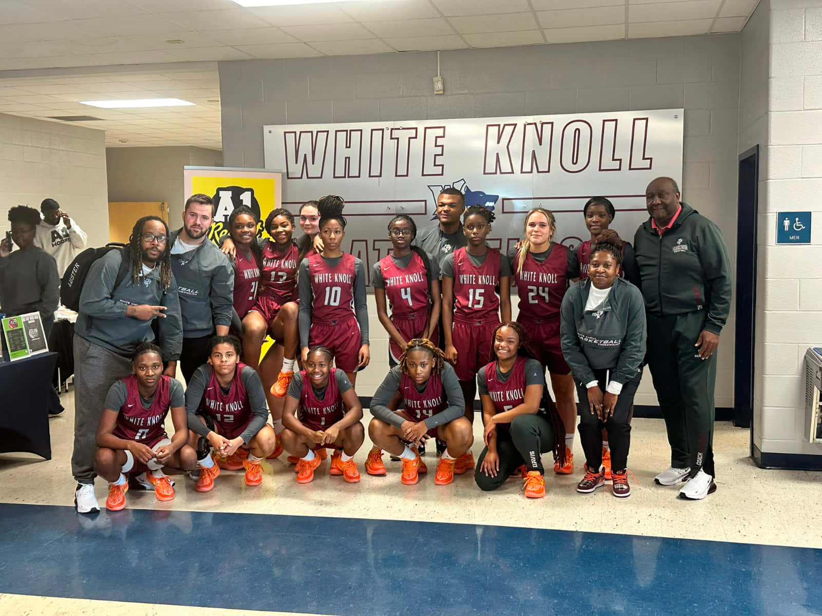 壁紙 — 一支籃球隊在學校走廊上拍照，身後掛著「WHITE KNOLL」的橫幅。