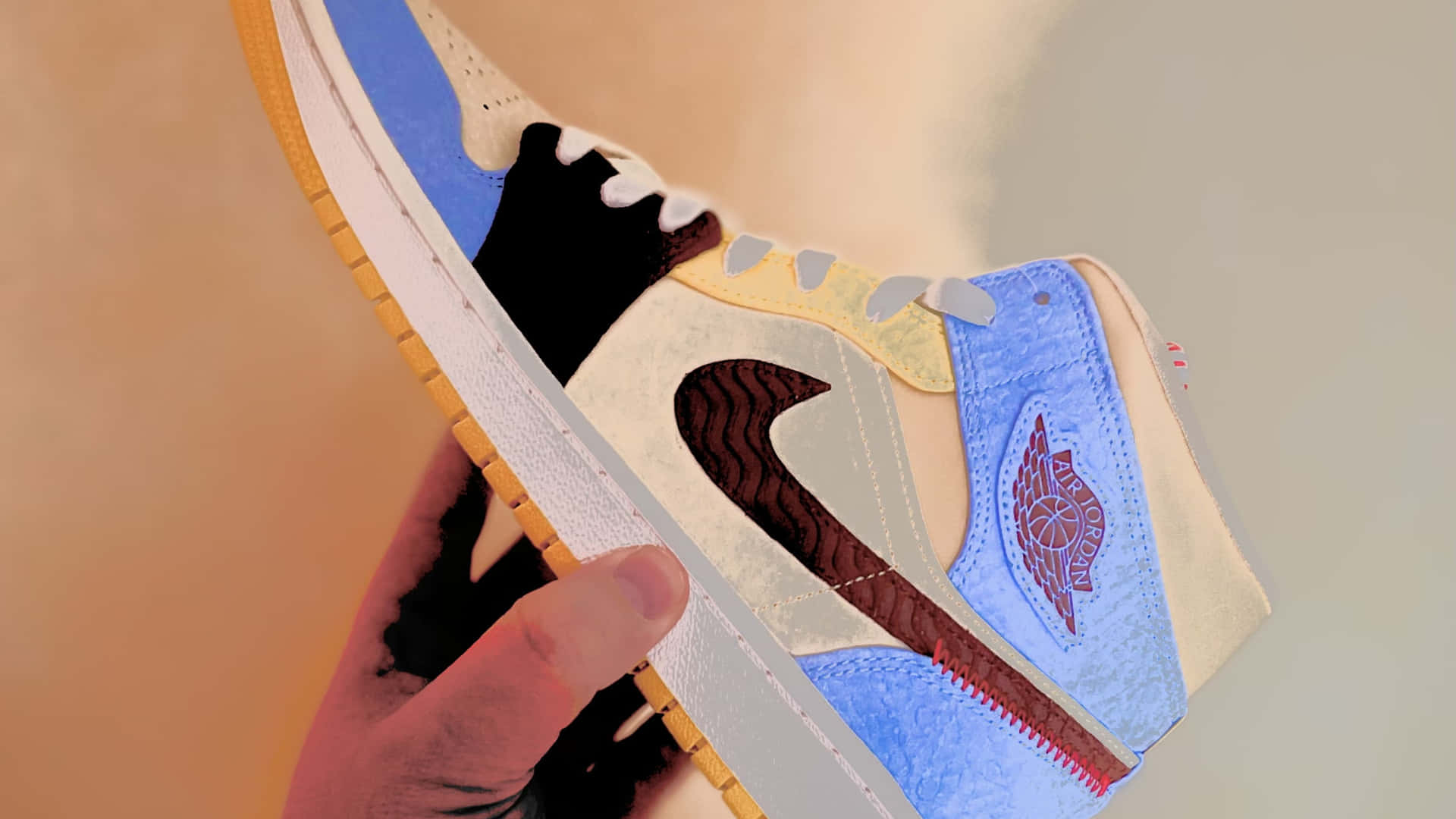 手拿著一雙藍色、米色、黑色復古Jordan運動鞋，帶紅色標誌。 — Jordan Logo 壁紙